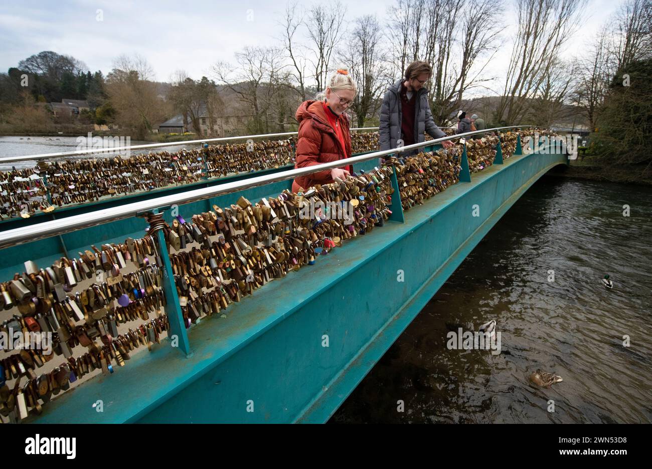 24/03/21 Mollie Edge et Jake Mycock recherchent et lisent les inscriptions sur les cadenas. Le pont Ôlove lockÕ Weir sur la rivière Wye à Bakewell. Banque D'Images