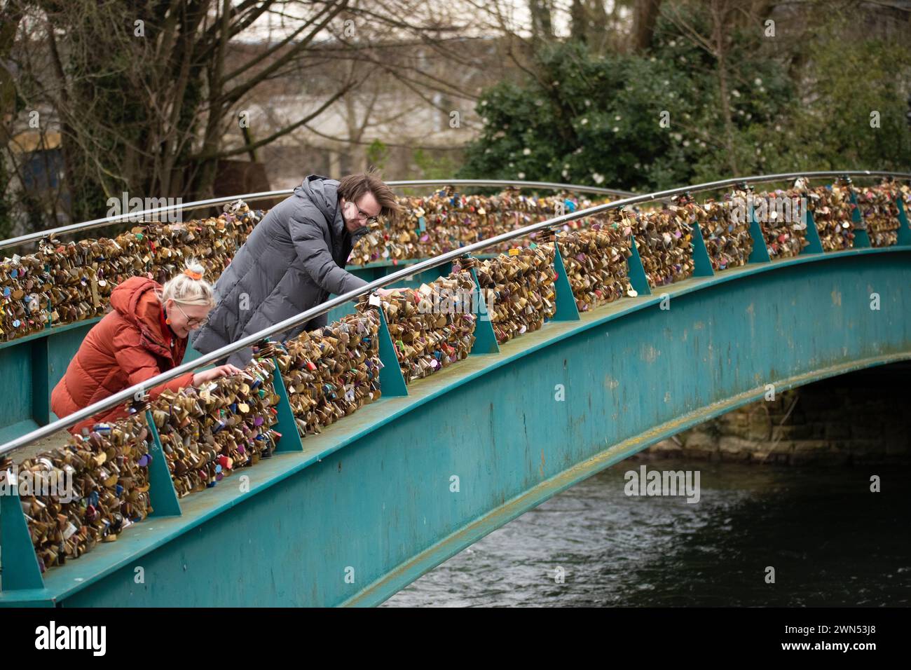 24/03/21 Mollie Edge et Jake Mycock recherchent et lisent les inscriptions sur les cadenas. Le pont Ôlove lockÕ Weir sur la rivière Wye à Bakewell. Banque D'Images