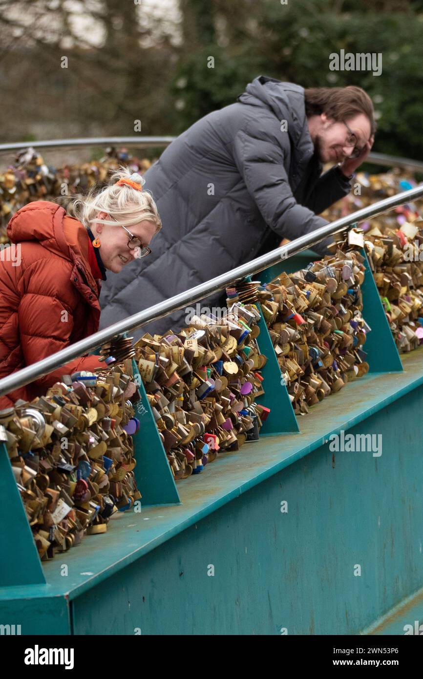 24/03/21 Mollie Edge et Jake Mycock recherchent et lisent les inscriptions sur les cadenas. Le pont Ôlove lockÕ Weir sur la rivière Wye à Bakewell. Banque D'Images
