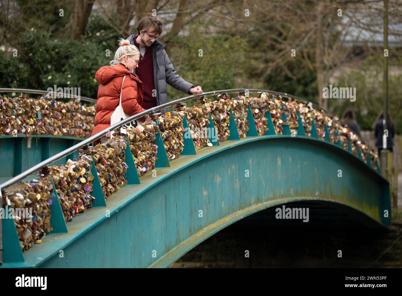 24/03/21 Mollie Edge et Jake Mycock recherchent et lisent les inscriptions sur les cadenas. Le pont Ôlove lockÕ Weir sur la rivière Wye à Bakewell. Banque D'Images
