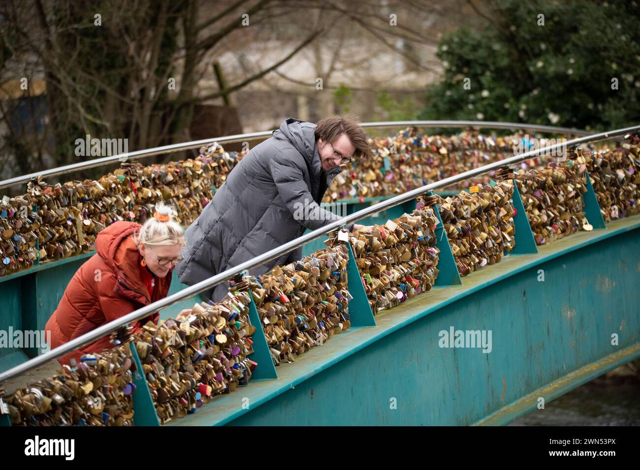 24/03/21 Mollie Edge et Jake Mycock recherchent et lisent les inscriptions sur les cadenas. Le pont Ôlove lockÕ Weir sur la rivière Wye à Bakewell. Banque D'Images