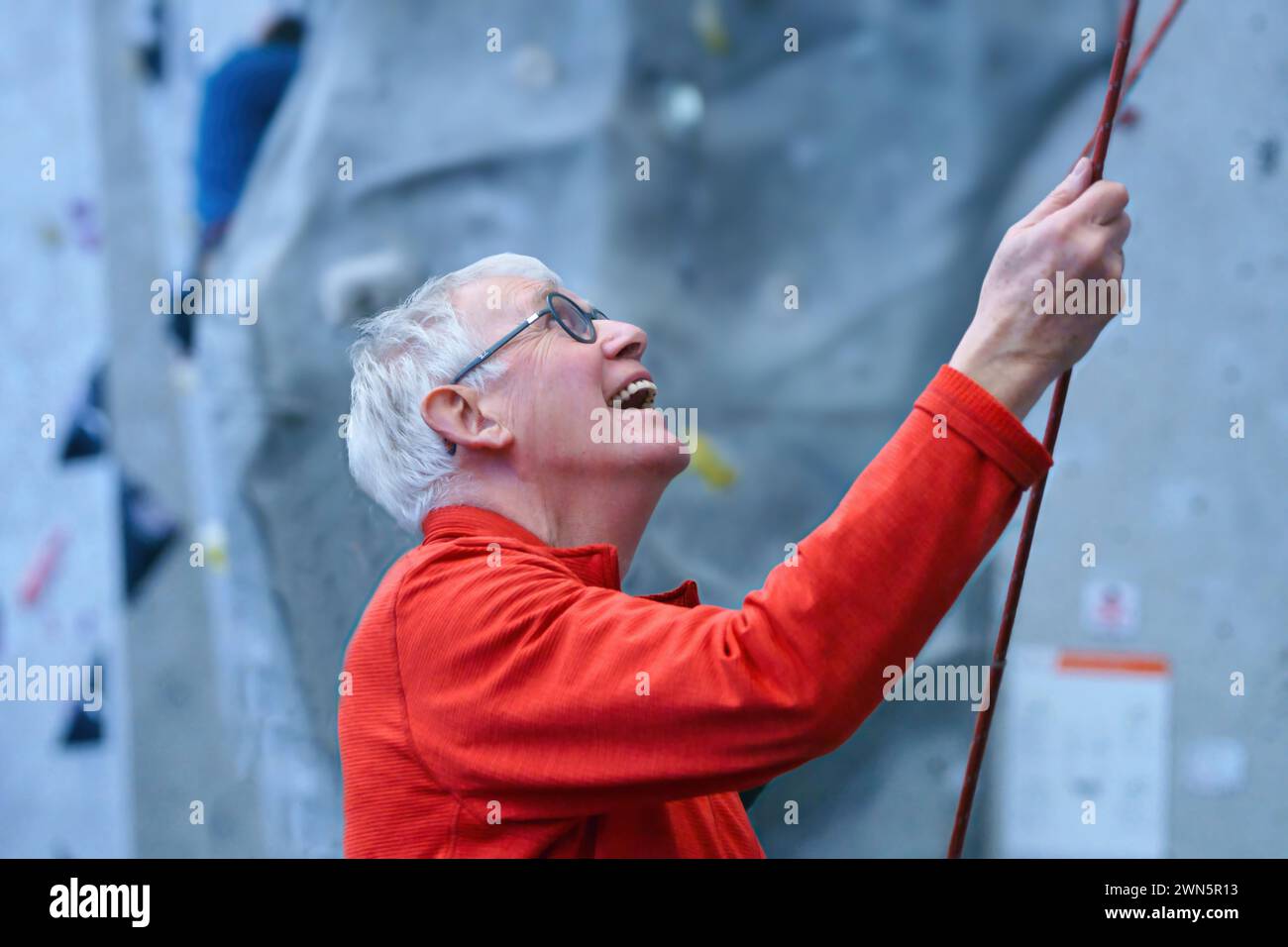 Grimpeur plus âgé démentant son partenaire à un mur d'escalade intérieur Banque D'Images