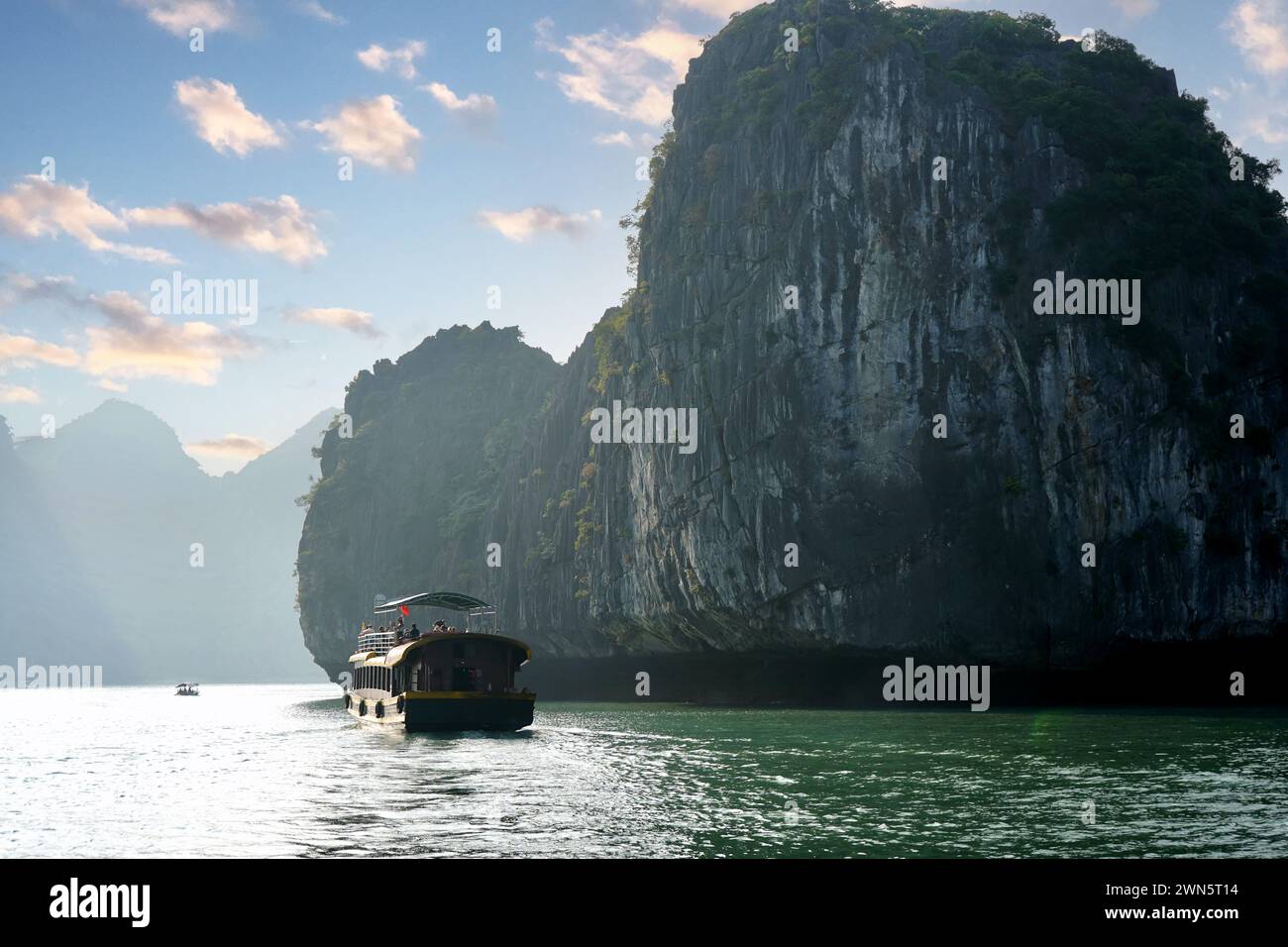 Petit bateau avec fond de falaises calcaires de la baie d'Halong Banque D'Images