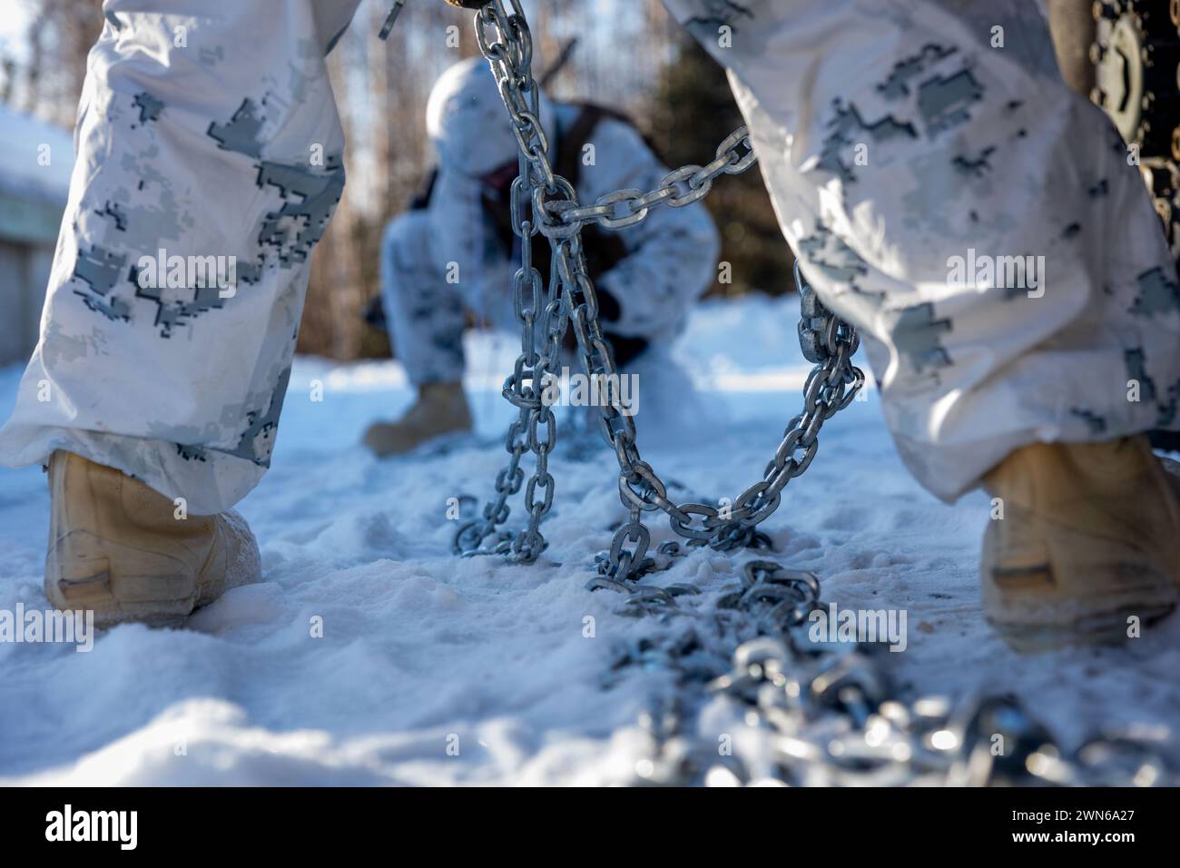 Les Marines américains avec Fox Battery, 2e bataillon, 14e régiment de Marines, 4e division des Marines, réserve des Forces marines attachent des chaînes à neige aux pneus d'un véhicule HIMARS (High Mobility Artillery Rocket System) avant d'entreprendre une infiltration rapide HIMARS, également connue sous le nom de HIRAIN, au cours de l’exercice Arctic Edge 2024 à la base aérienne d’Eielson, Alaska, le 24 février 2024. Le système d'armes HIMARS est un élément crucial de l'élément de combat au sol de la Marine Air-Ground Task Force (MAGTF). Les HIMARS jouent un rôle central dans la fourniture de feux de précision à longue portée pour soutenir les objectifs de la MAGTF, depuis Expeditionary Banque D'Images