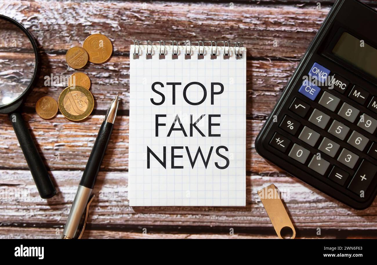 Femme tenant le mégaphone et la plaque avec le texte ARRÊTER LES FAUSSES NOUVELLES sur fond sombre. Banque D'Images