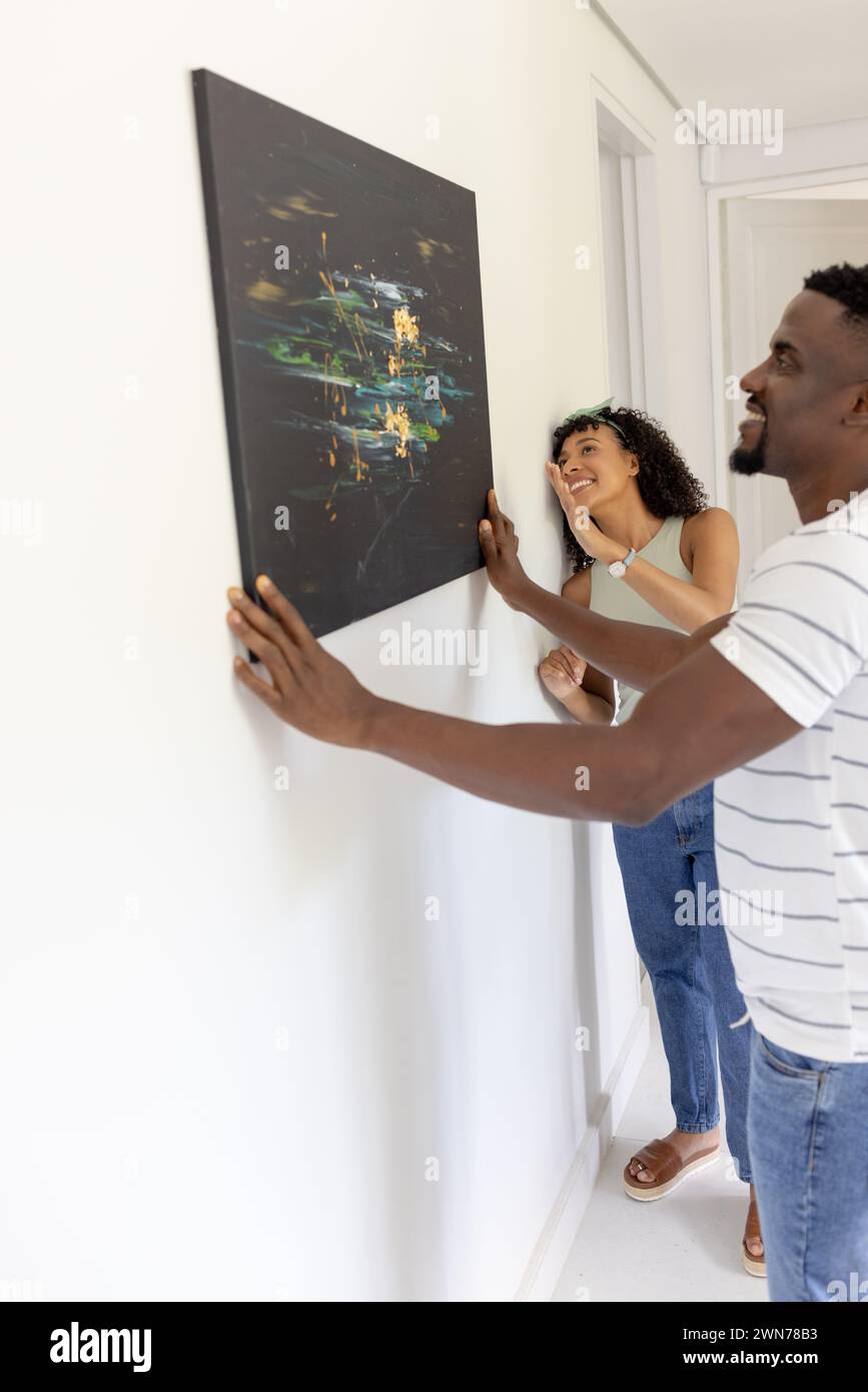 Couple afro-américain biracial accroche une peinture abstraite noire à la maison avec espace de copie Banque D'Images