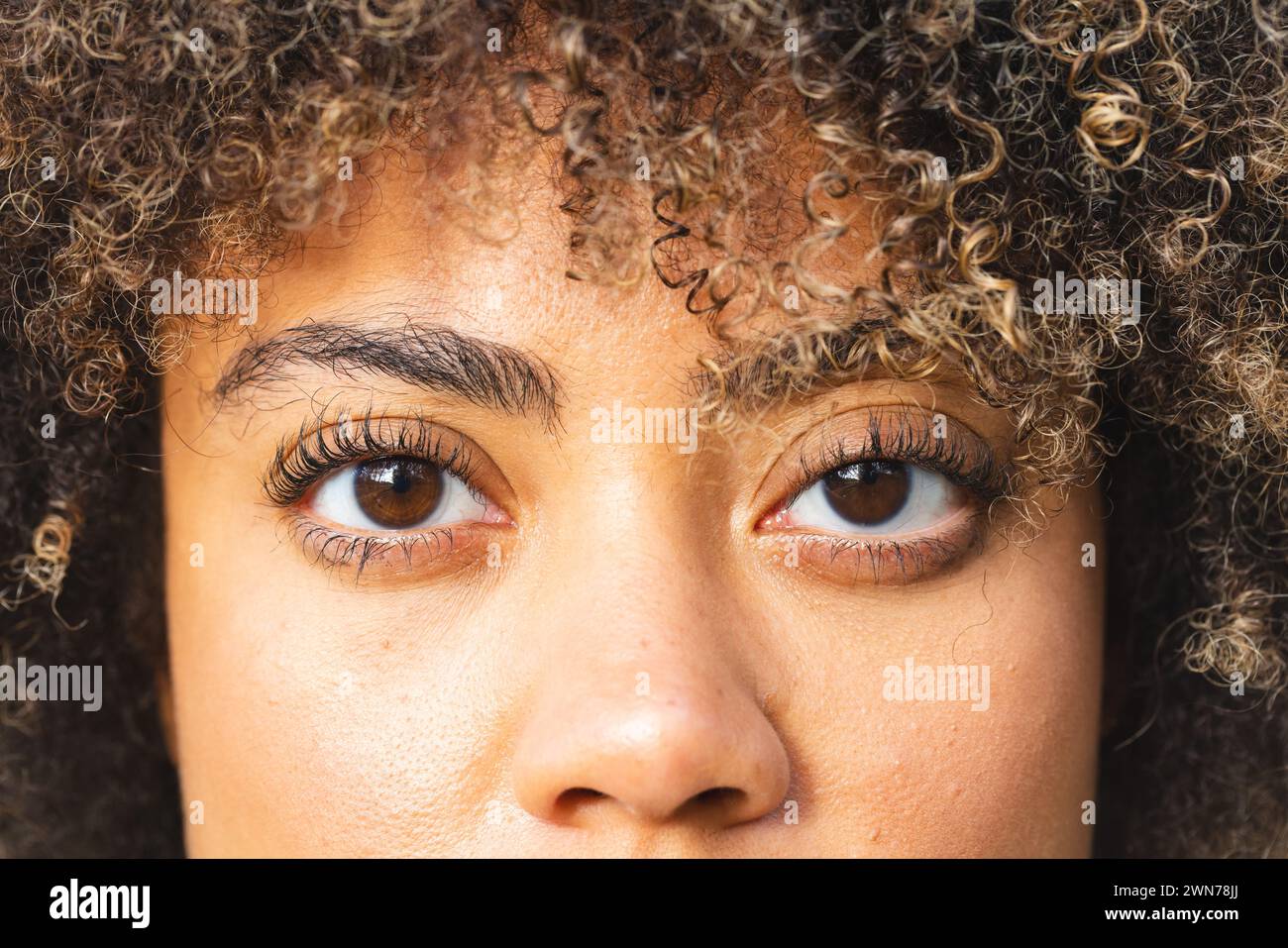Gros plan d'une jeune femme biraciale avec les cheveux bouclés et les yeux bruns sur une randonnée Banque D'Images