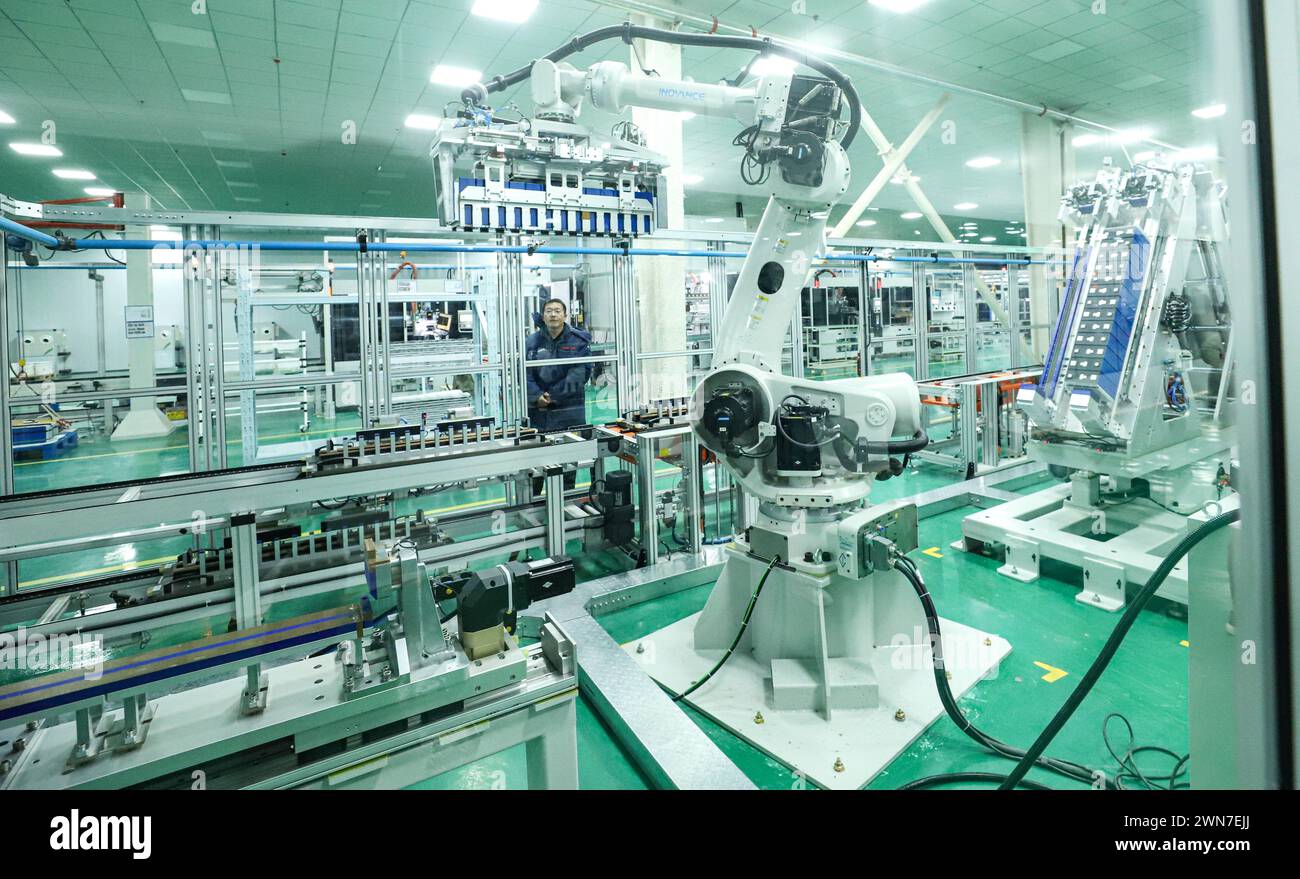ZHANGYE, CHINE - 29 FÉVRIER 2024 - Un membre du personnel observe le fonctionnement d'un robot de module de stockage d'énergie sur une ligne de production automatisée pour e. Banque D'Images