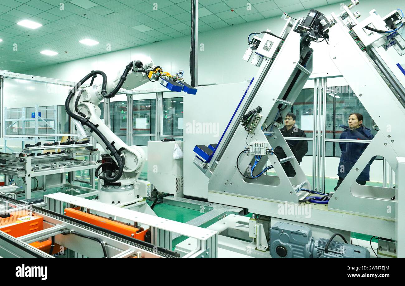 ZHANGYE, CHINE - 29 FÉVRIER 2024 - Un membre du personnel observe le fonctionnement d'un robot de module de stockage d'énergie sur une ligne de production automatisée pour e. Banque D'Images