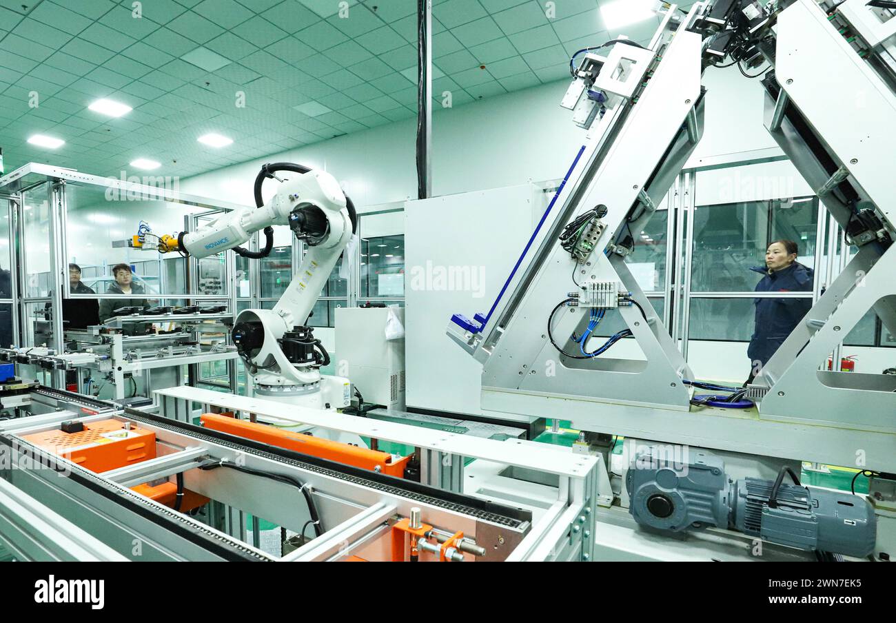 ZHANGYE, CHINE - 29 FÉVRIER 2024 - Un membre du personnel observe le fonctionnement d'un robot de module de stockage d'énergie sur une ligne de production automatisée pour e. Banque D'Images