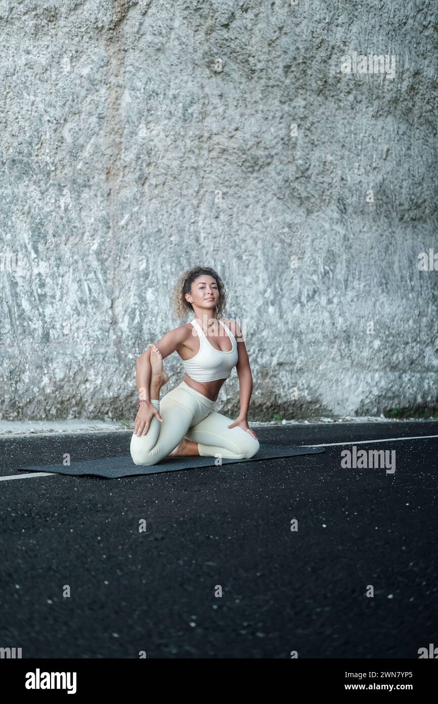 Une jeune femme latina fait un asana de yoga sur fond de rocher blanc. Banque D'Images
