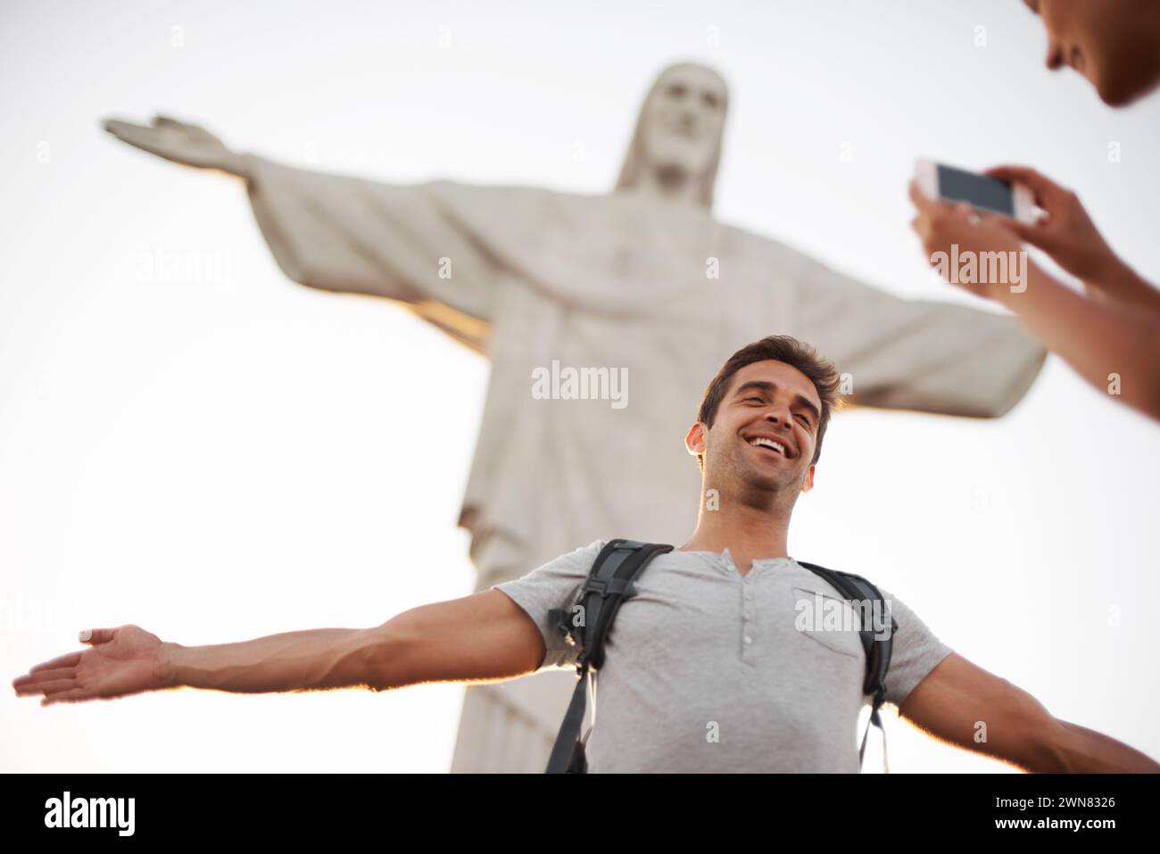 Homme, photo et voyage par le christ rédempteur, crucifier et heureux dans la culture chrétienne en vacances. Sculpture de Jésus, rio ou Guy pour la mise à jour des médias sociaux Banque D'Images