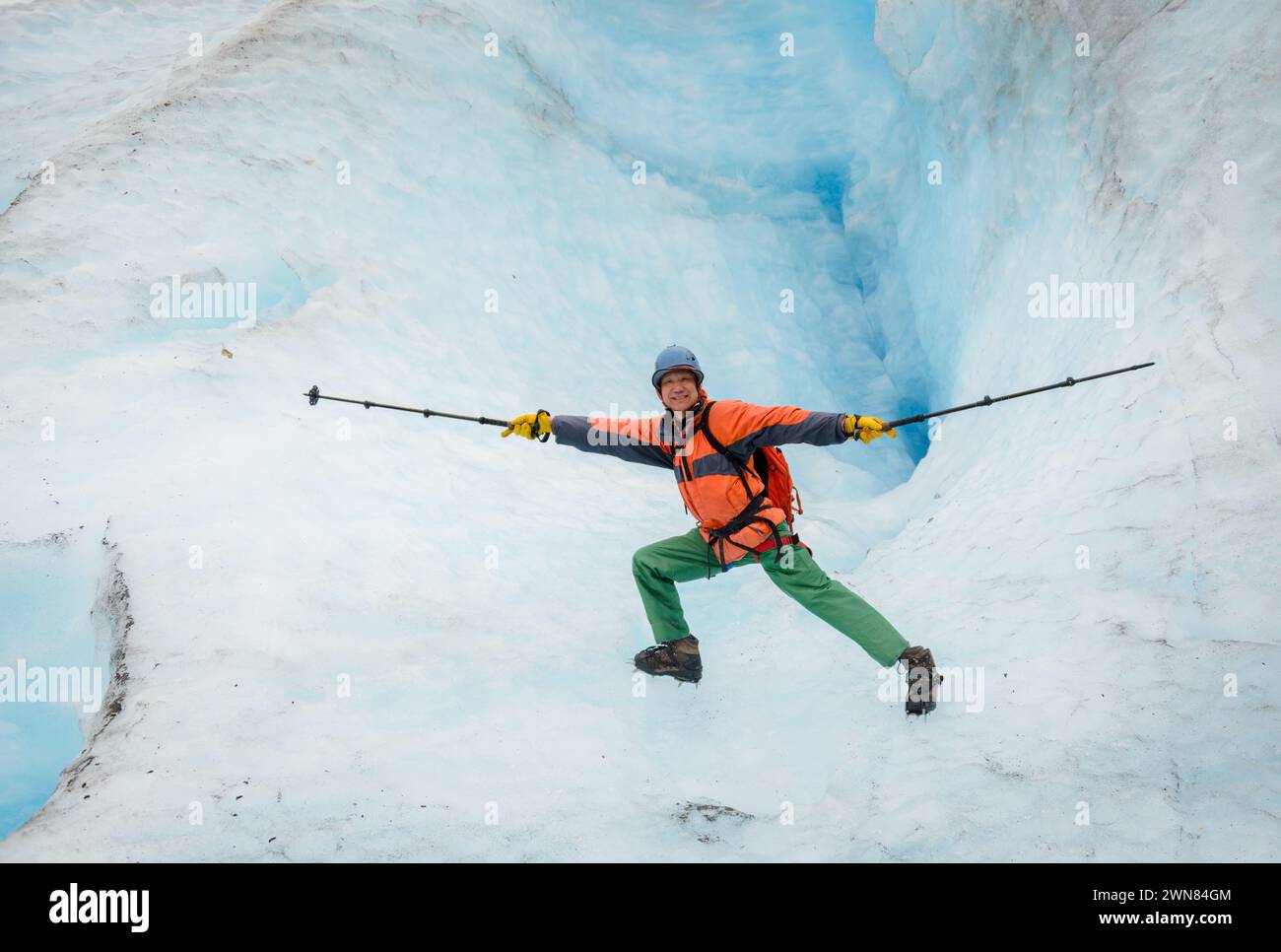 Homme tenant des bâtons de randonnée et faisant des poses de yoga devant un gouffre de glace. Sortez à Glacier. Parc national de Kenai Fjords. Alaska. Banque D'Images
