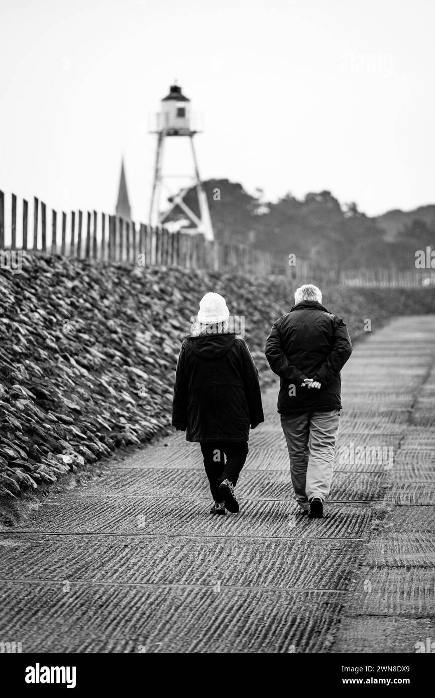 Un couple marchant le long des défenses maritimes à Silloth, Cumbria, Angleterre, Royaume-Uni Banque D'Images