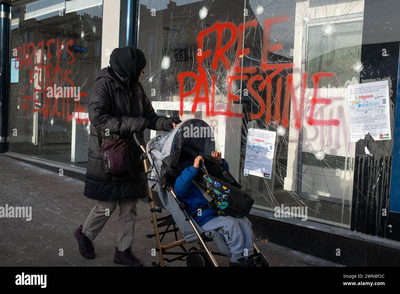 Glasgow, Royaume-Uni, 1er mars 2024. Fenêtres brisées et graffitis lisant « Barcleys Funds génocide » et « Free Palestine » sur la Barclays Bank dans le quartier Shawlands de Glasgow, en Écosse, le 1er mars 2024. Photo de Jeremy Sutton-Hibbert/Alamy Live News. Banque D'Images