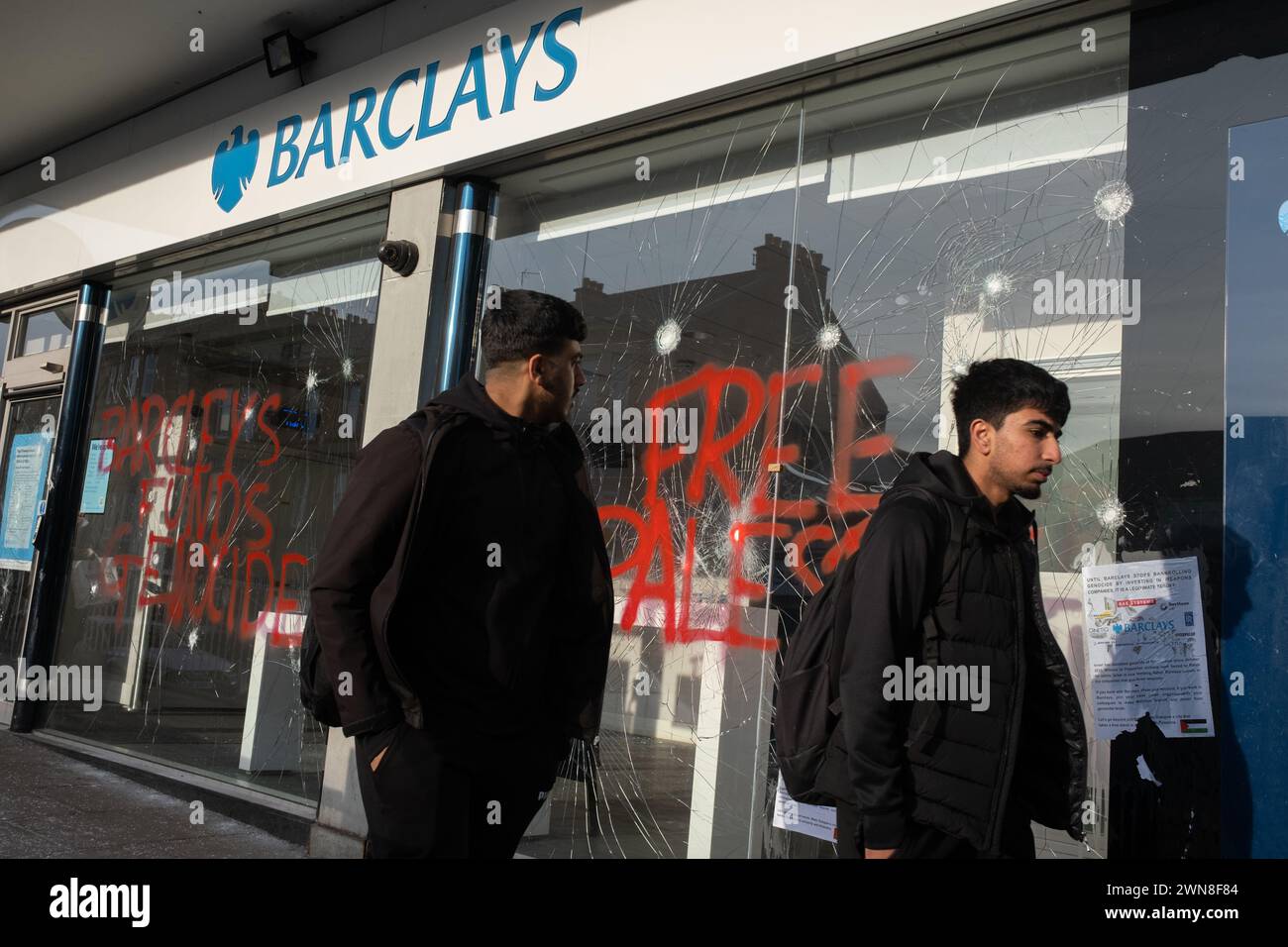 Glasgow, Royaume-Uni, 1er mars 2024. Fenêtres brisées et graffitis lisant « Barcleys Funds génocide » et « Free Palestine » sur la Barclays Bank dans le quartier Shawlands de Glasgow, en Écosse, le 1er mars 2024. Photo de Jeremy Sutton-Hibbert/Alamy Live News. Banque D'Images