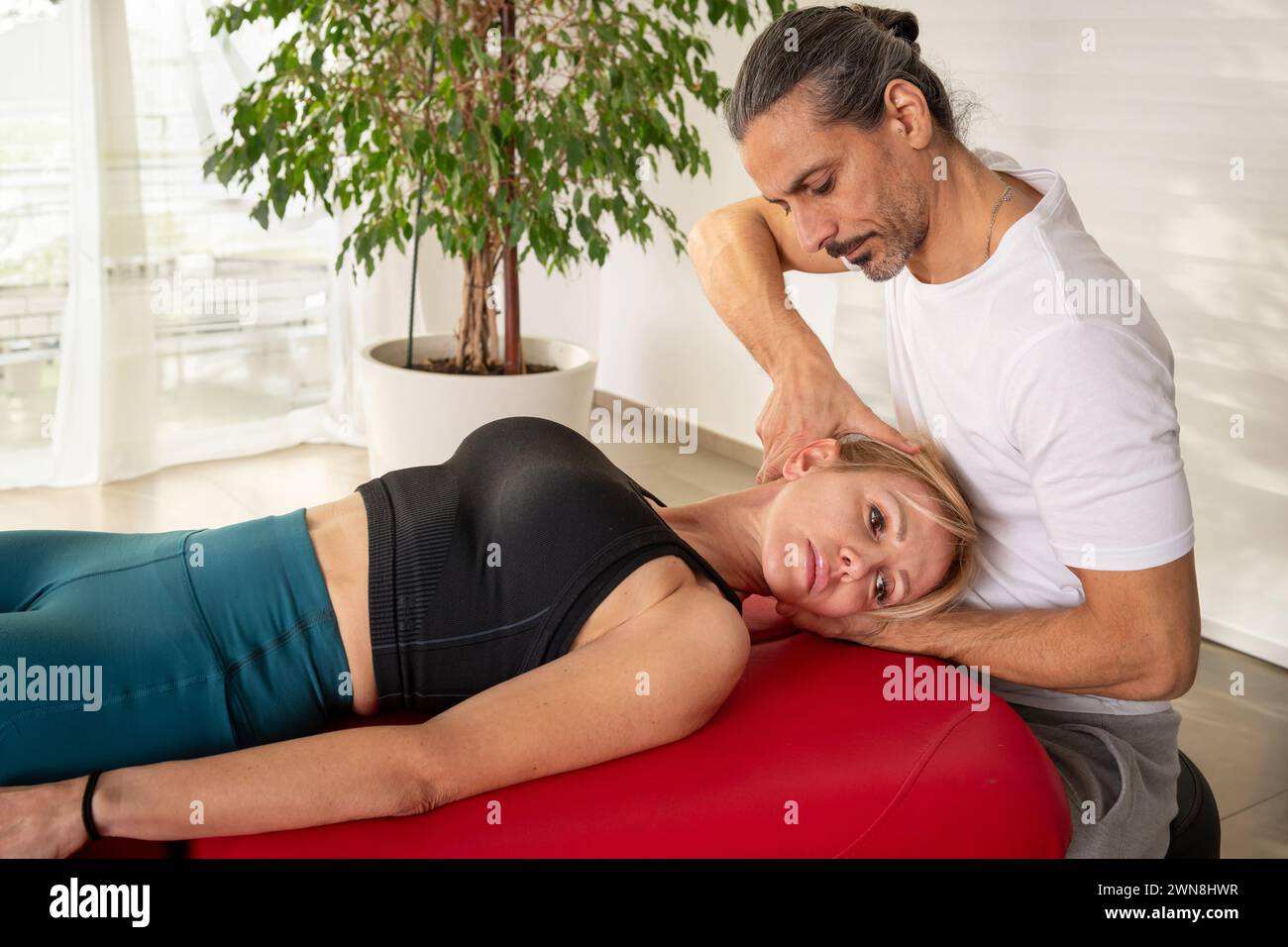 Physiothérapeute concentré manipulant la colonne vertébrale du patient pour soulager les douleurs cervicales en médecine alternative lors de la consultation en clinique moderne Banque D'Images