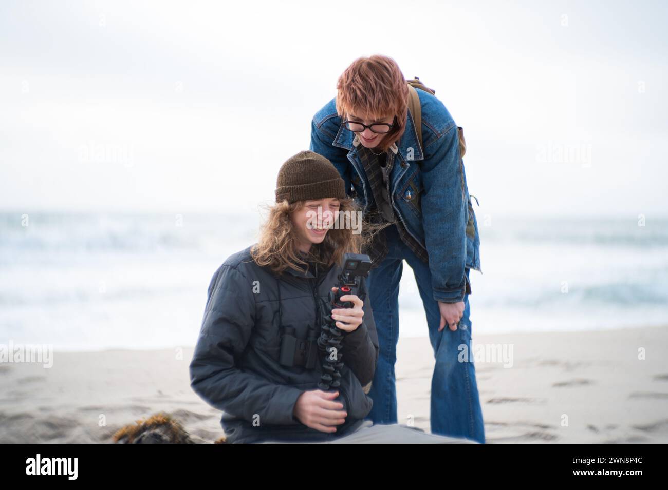 Frères et sœurs souriants regardant l'arrière de la caméra embarquée sur la plage Banque D'Images