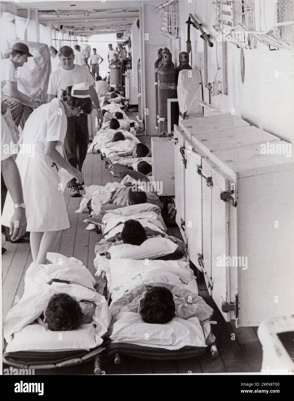 Mer de Chine méridionale. Une infirmière de la Marine assiste les malades et les blessés sur des civières sur le pont du navire-hôpital USS Sanctuary (AH-17) amarré dans le port de Da Nang. Les hommes viennent d'arriver à bord par un hélicoptère d'évacuation sanitaire. Corps infirmier à bord des navires hospitaliers.04/1970; Banque D'Images