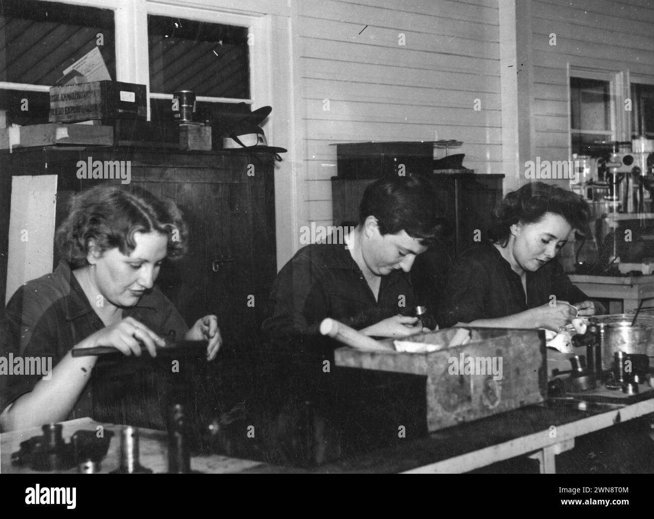 Photographies vintage de femmes en formation pour les usines de travail pendant la seconde Guerre mondiale, une partie de l'importante contribution des femmes aux efforts de guerre. Queensland, Australie 1945. Des femmes, membres de l'Australian Women's Army Service, assemblant des viseurs d'armes à feu dans un atelier de mécanique électrique de l'armée Banque D'Images