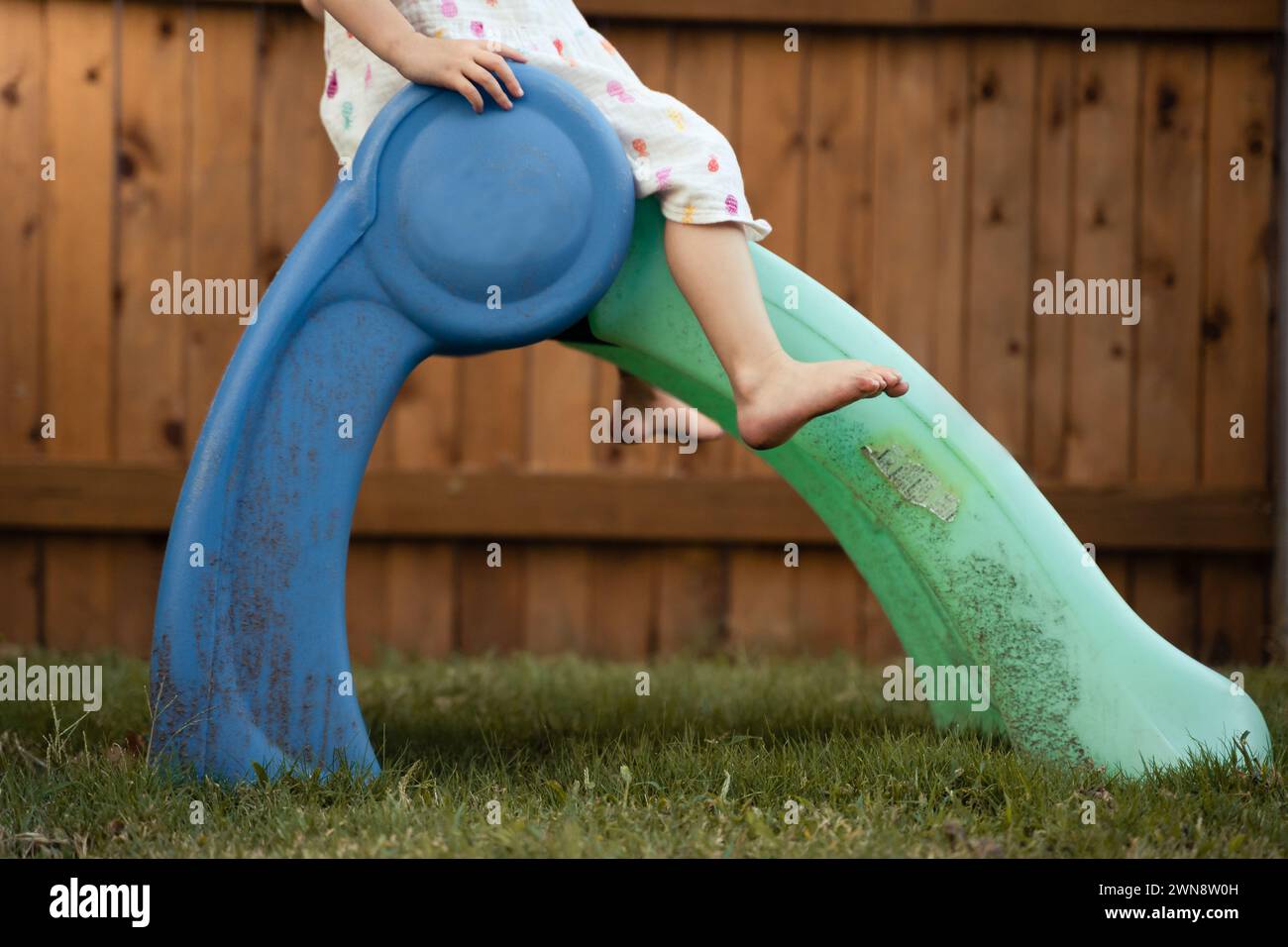 Petite fille glissant vers le bas Toy Slide dans la cour arrière Banque D'Images