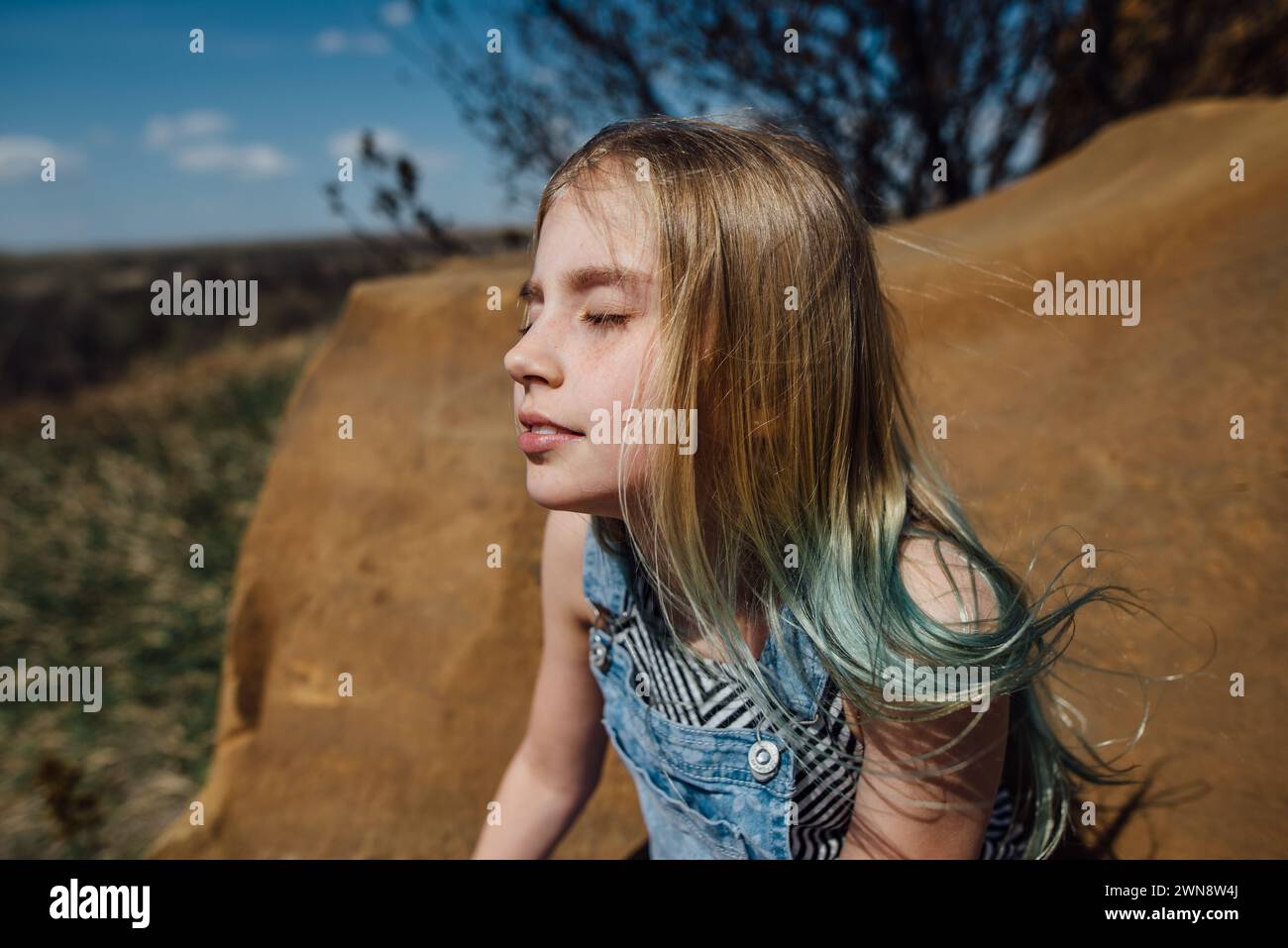 Preteen Girl est assis paisiblement dans la nature avec les yeux fermés. Banque D'Images
