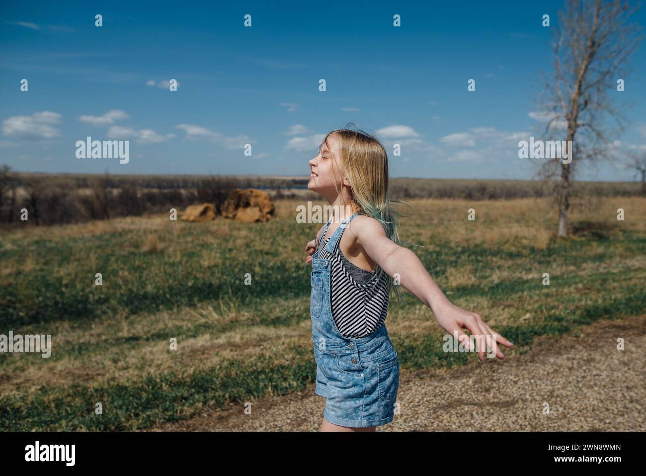 Preteen Girl se prélasse au soleil sur la route de campagne rurale en été. Banque D'Images