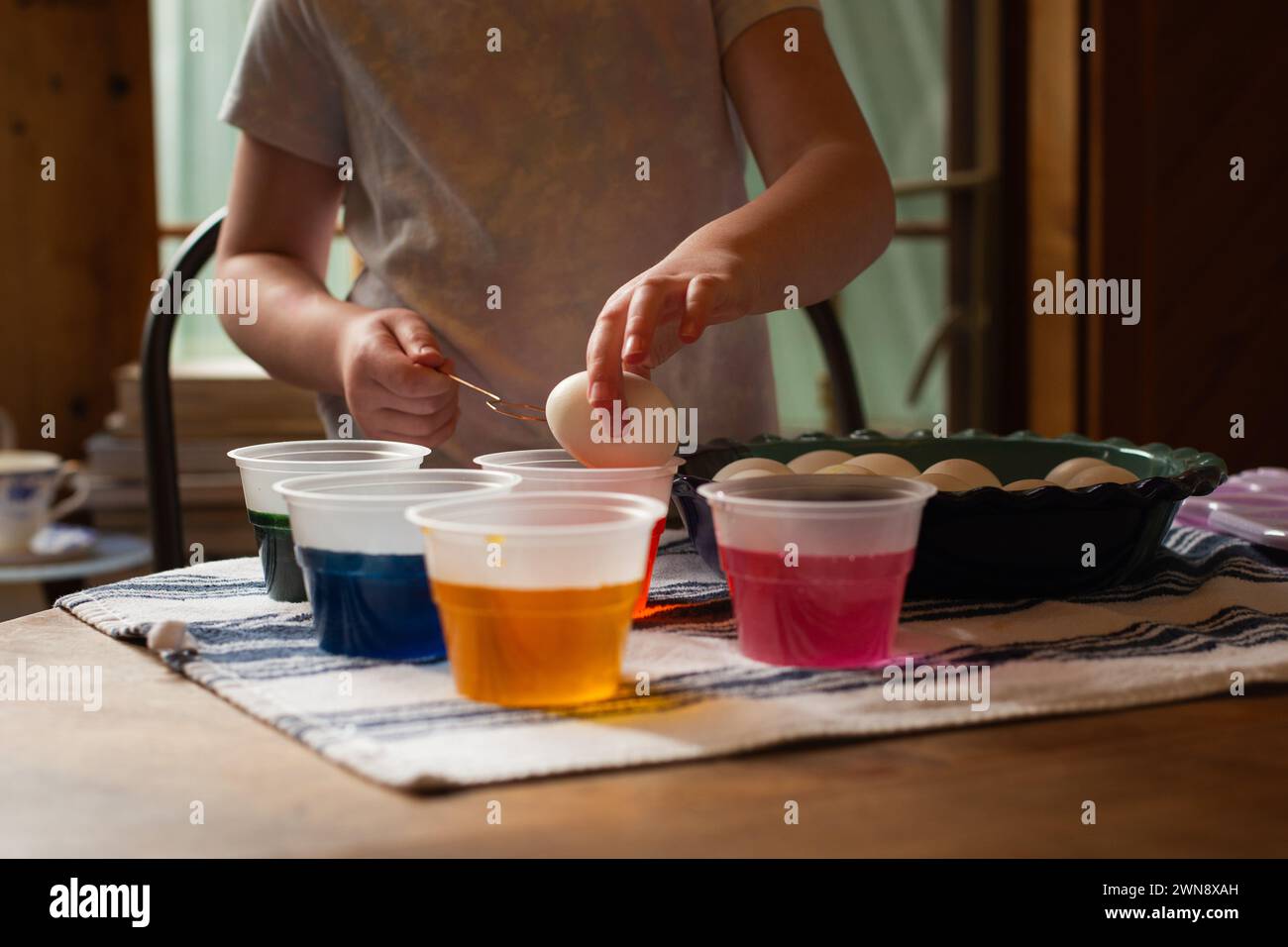 Un enfant trempe des oeufs de Pâques dans un colorant alimentaire Banque D'Images