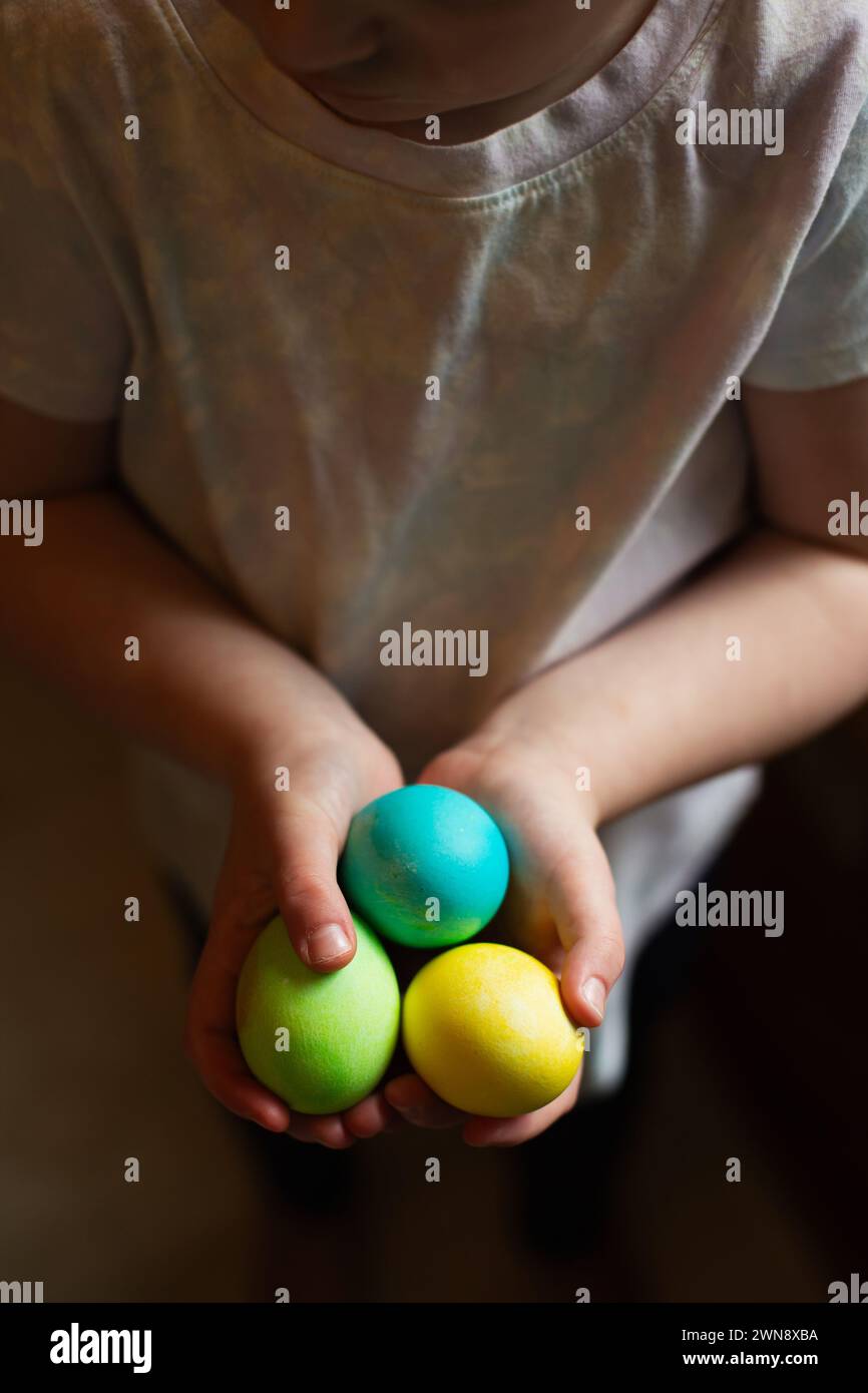 Visage et bras de l'enfant tenant des oeufs de Pâques colorés Banque D'Images