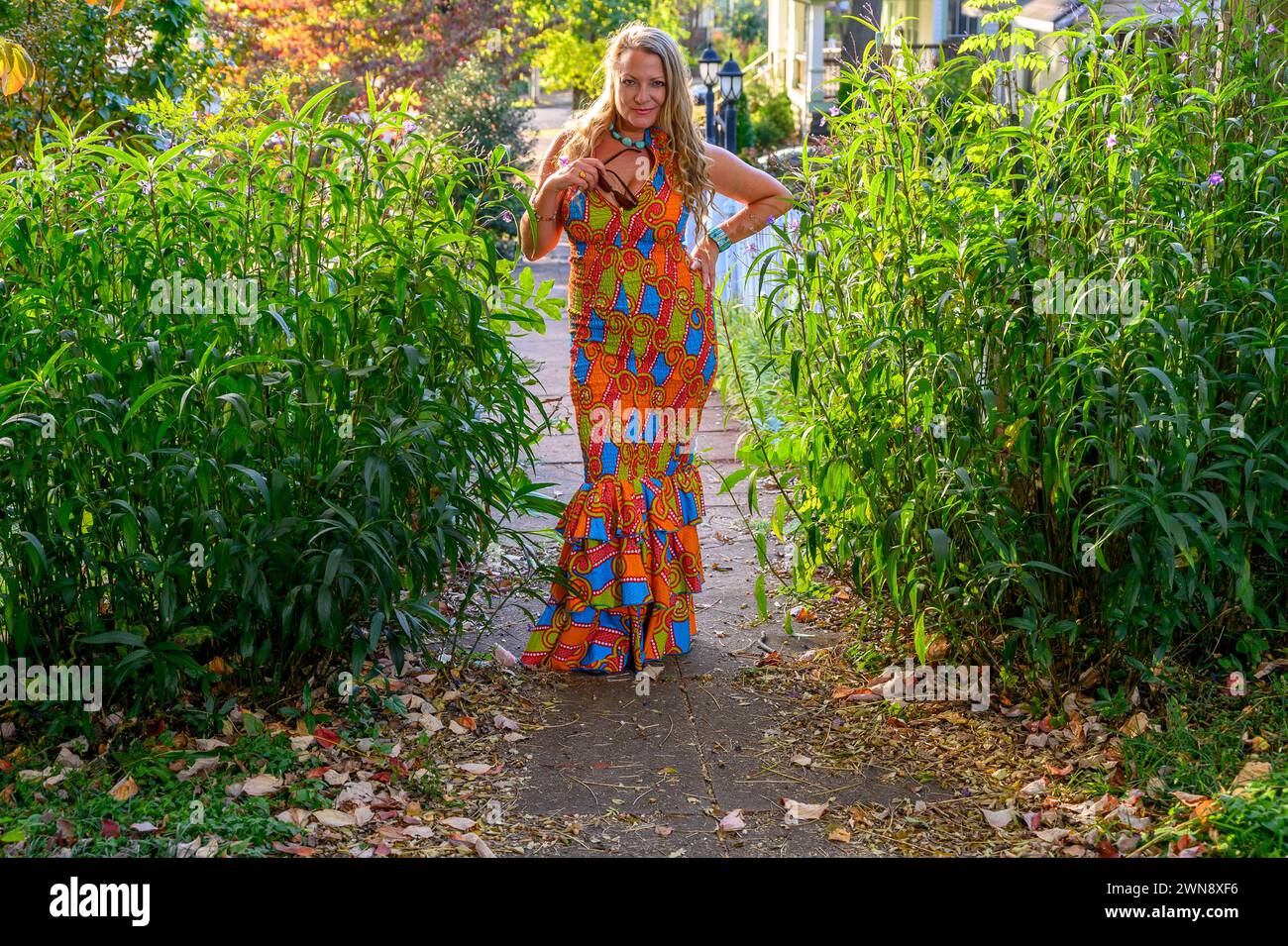 femme blonde de 40 ans posant dans une robe colorée à l'extérieur. Banque D'Images