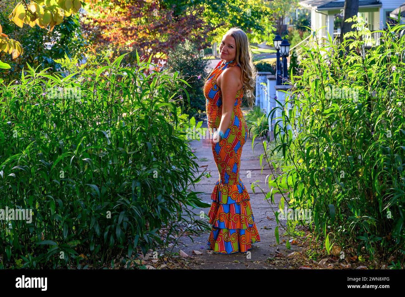 femme blonde de 40 ans posant dans une robe colorée à l'extérieur. Banque D'Images