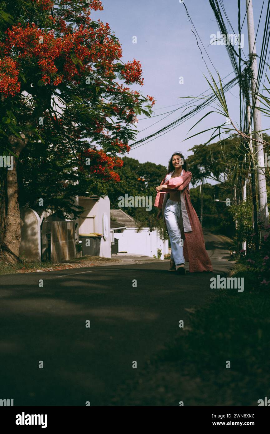 Une jeune femme aux cheveux longs dans un kimono marche dans la rue à Bali. Banque D'Images