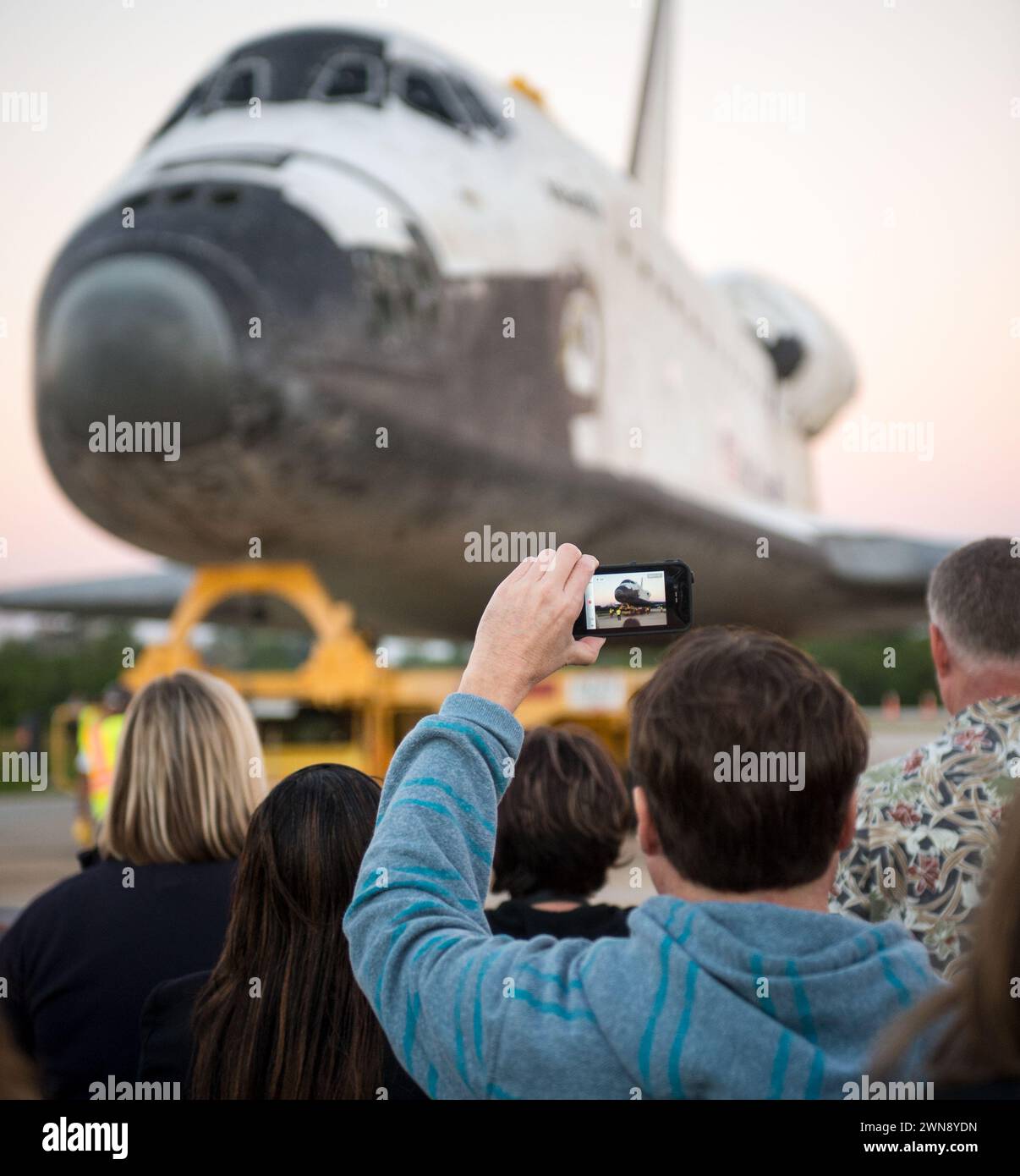 Un spectateur tient un appareil mobile pour enregistrer la navette spatiale Atlantis alors qu'elle roule vers sa nouvelle maison au Kennedy Space Center Visitor Complex, tôt vendredi 2 novembre 2012, à Cape Canaveral, Fla. Le vaisseau spatial a parcouru 125 935 769 miles au cours de 33 vols spatiaux, dont 12 missions à destination de la Station spatiale internationale. Son dernier vol, le STS-135, a clôturé l'ère du programme de navette spatiale avec un atterrissage le 21 juillet 2011. Crédit photo : (NASA/Bill Ingalls) Banque D'Images