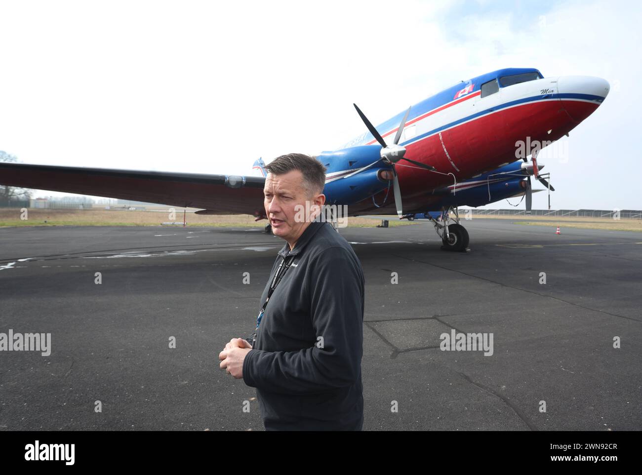 Giebelstadt, Allemagne. 01 mars 2024. Andrew Searle, directeur de vol de Bell Geospace Limited, se tient devant un Douglas DC-3 converti de 1943 à l'aéroport de Giebelstadt. L’avion, équipé de la technologie de mesure la plus récente, sera utilisé dans les semaines à venir pour collecter des informations géophysiques sur les propriétés de la roche souterraine dans les régions de Würzburg et de Nuremberg afin d’explorer le potentiel d’utilisation d’une énergie géothermique respectueuse de l’environnement. Crédit : Karl-Josef Hildenbrand/dpa/Alamy Live News Banque D'Images