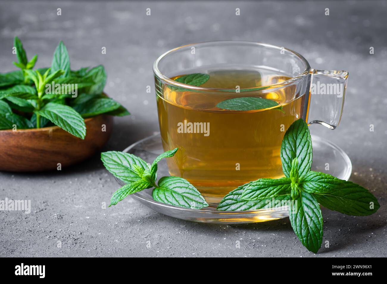 Tasse de thé à la menthe avec des feuilles de menthe verte fraîche sur une table rustique, boisson chaude saine à base de plantes Banque D'Images