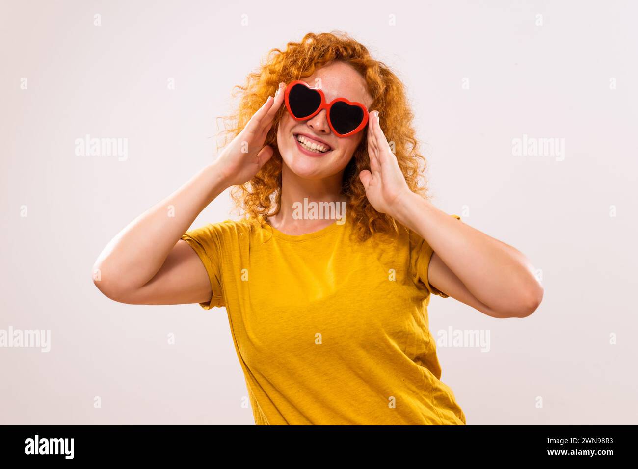 Image de femme heureuse de gingembre avec des lunettes de soleil en forme de coeur rouge. Banque D'Images
