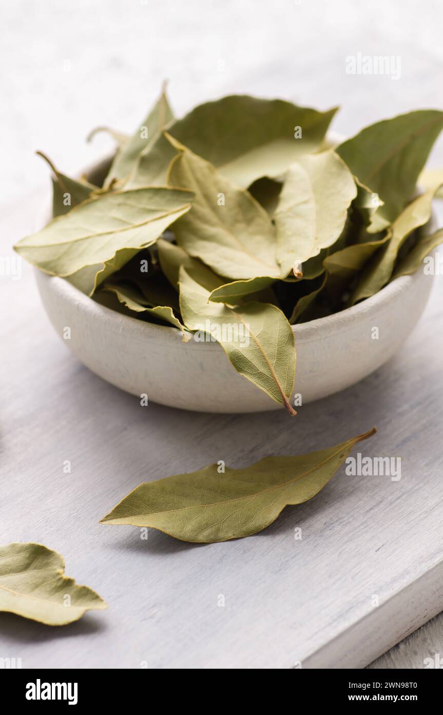 Feuilles de laurier séchées dans un bol sur fond rustique, concept d'épices et d'herbes (Laurus nobilis) Banque D'Images