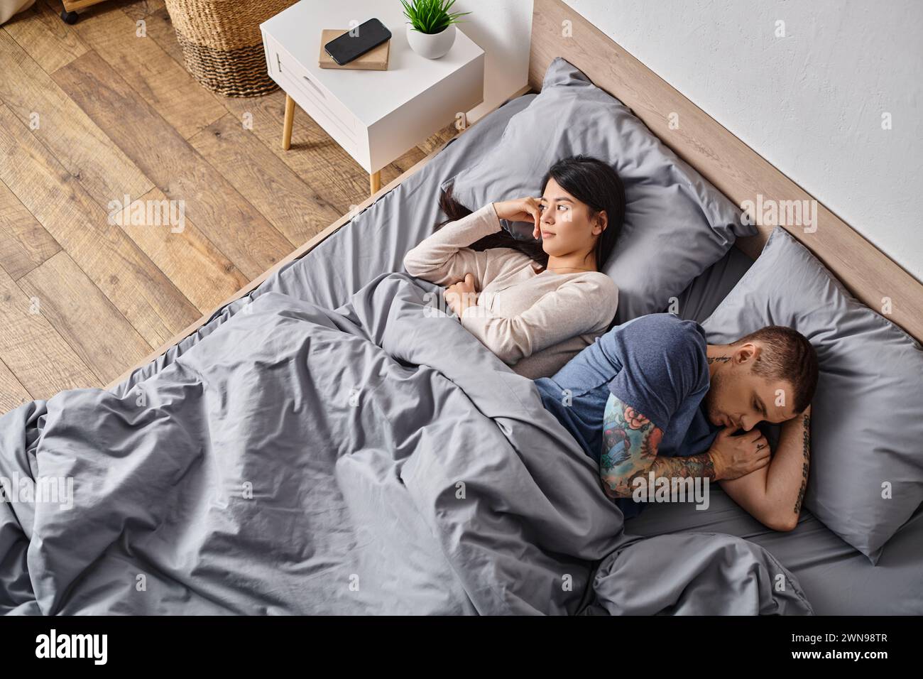 vue en angle élevé de la femme asiatique et de l'homme tatoué couché sur le lit, concept de difficultés relationnelles Banque D'Images