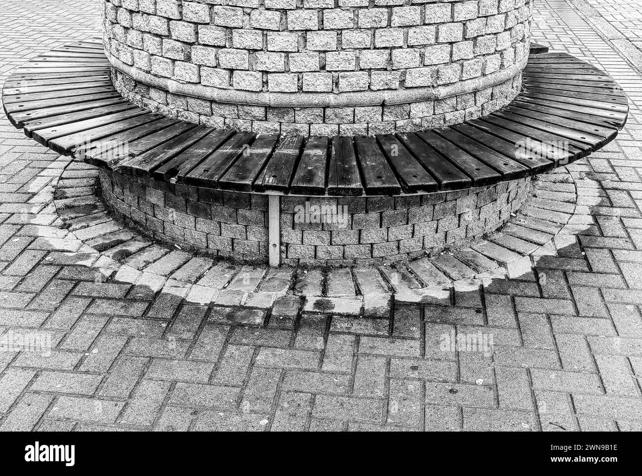 Sérénité circulaire. Planche en bois et banc de ville pavé. Noir et blanc, Monochrome. Banque D'Images