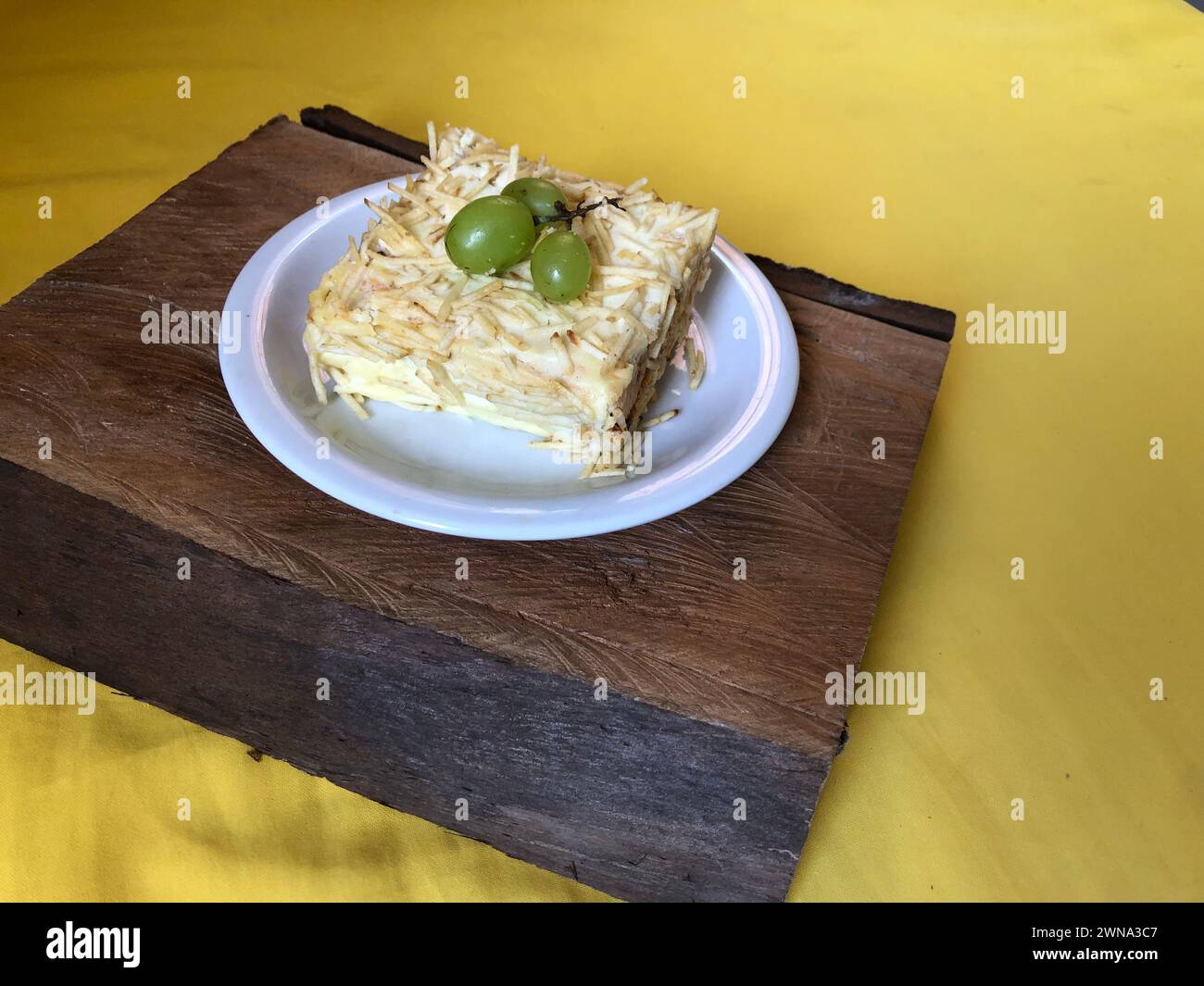 Délicieuse tarte froide au poulet garnie de purée de pommes de terre et de raisins sur une planche à découper en bois rustique avec espace de copie Banque D'Images