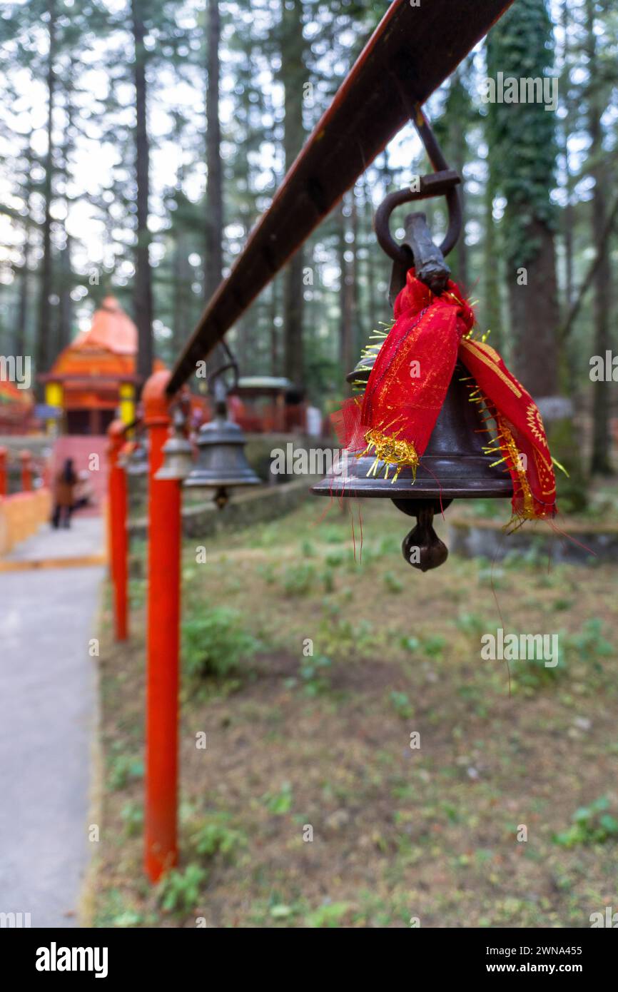 Cloches de bronze avec des tissus rouges : symbolisme spirituel au temple Tarkeshwar Mahadev, Uttarakhand, Inde Banque D'Images