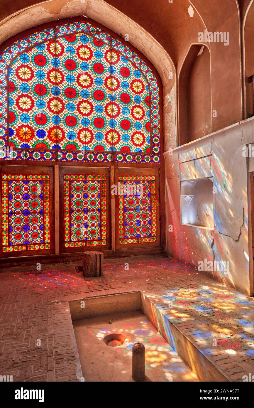 Le vitrail orné projette des éclaboussures de lumière colorées sur le mur et le sol du pavillon. Jardin de Dowlatabad, Yazd, Iran. Banque D'Images