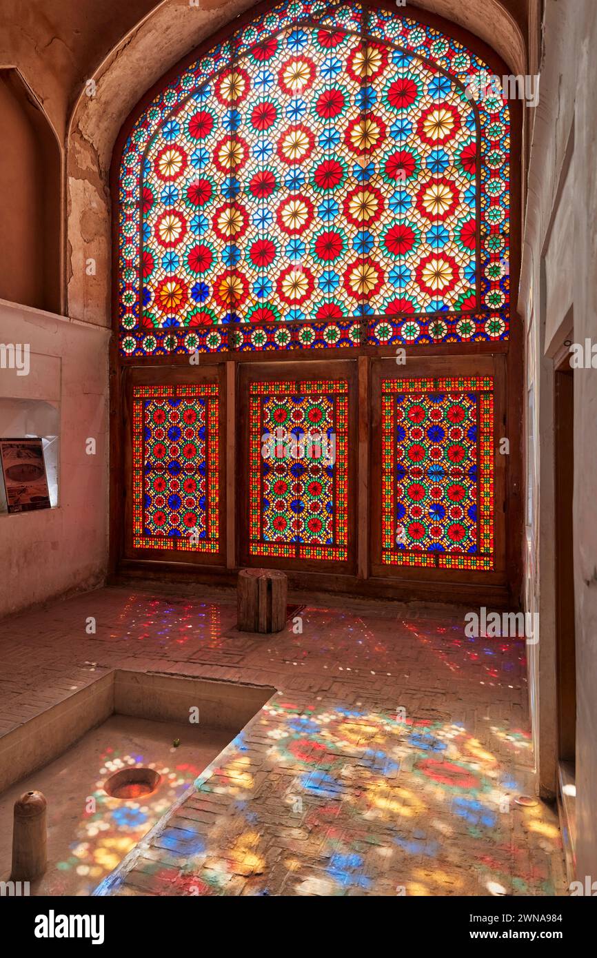 Un grand vitrail orné projette des éclaboussures de lumière colorées sur le sol du pavillon. Jardin de Dowlatabad, Yazd, Iran. Banque D'Images