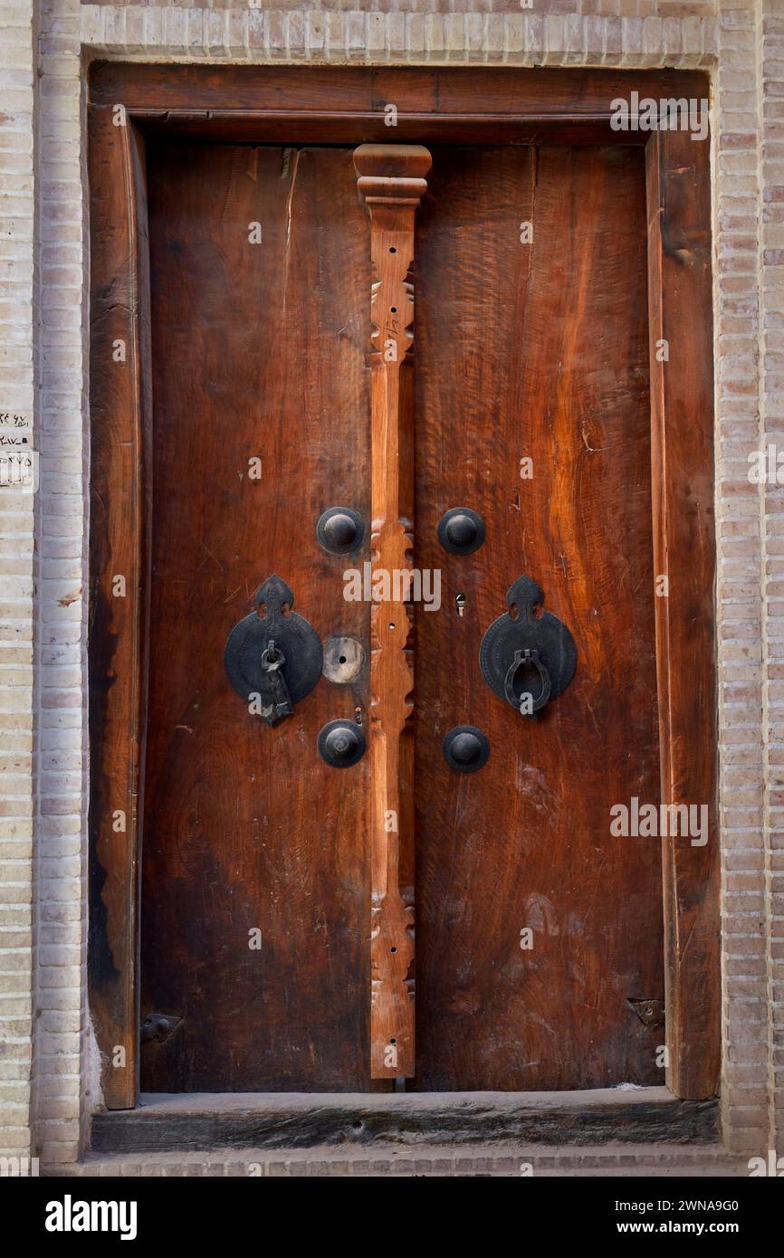 Vieille porte d'entrée en bois avec deux frappeurs séparés - barre en métal pour les hommes et anneau en métal pour les femmes. Yazd, Iran. Banque D'Images