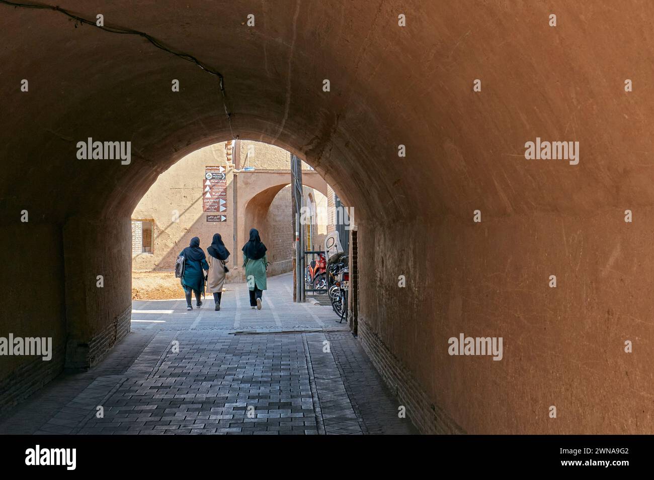 Trois femmes locales marchent ensemble dans une rue étroite de la vieille ville de Yazd, en Iran. Banque D'Images