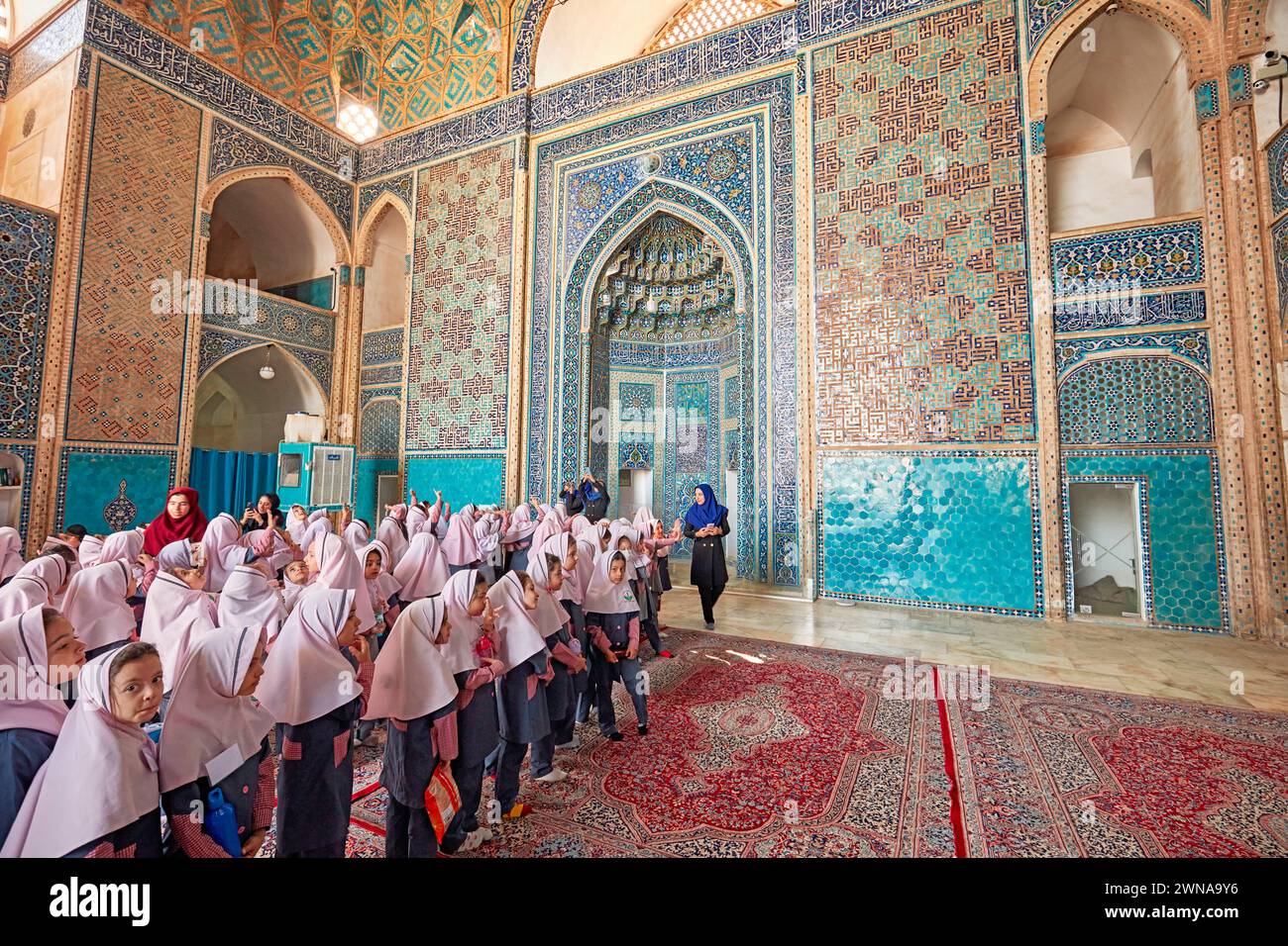Petites écolières iraniennes en uniforme scolaire avec des hijabs roses à l'intérieur de la mosquée Jameh de Yazd, mosquée chiite du XIVe siècle dans la vieille ville de Yazd, Iran. Banque D'Images