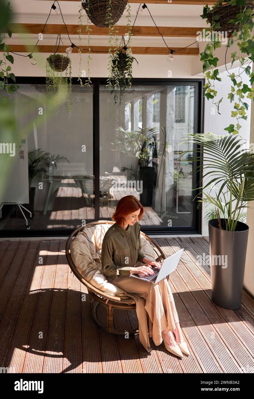 Femme d'affaires utilisant un ordinateur portable travaillant dans la chaise dans le bureau vert. Vue de dessus, verticale Banque D'Images