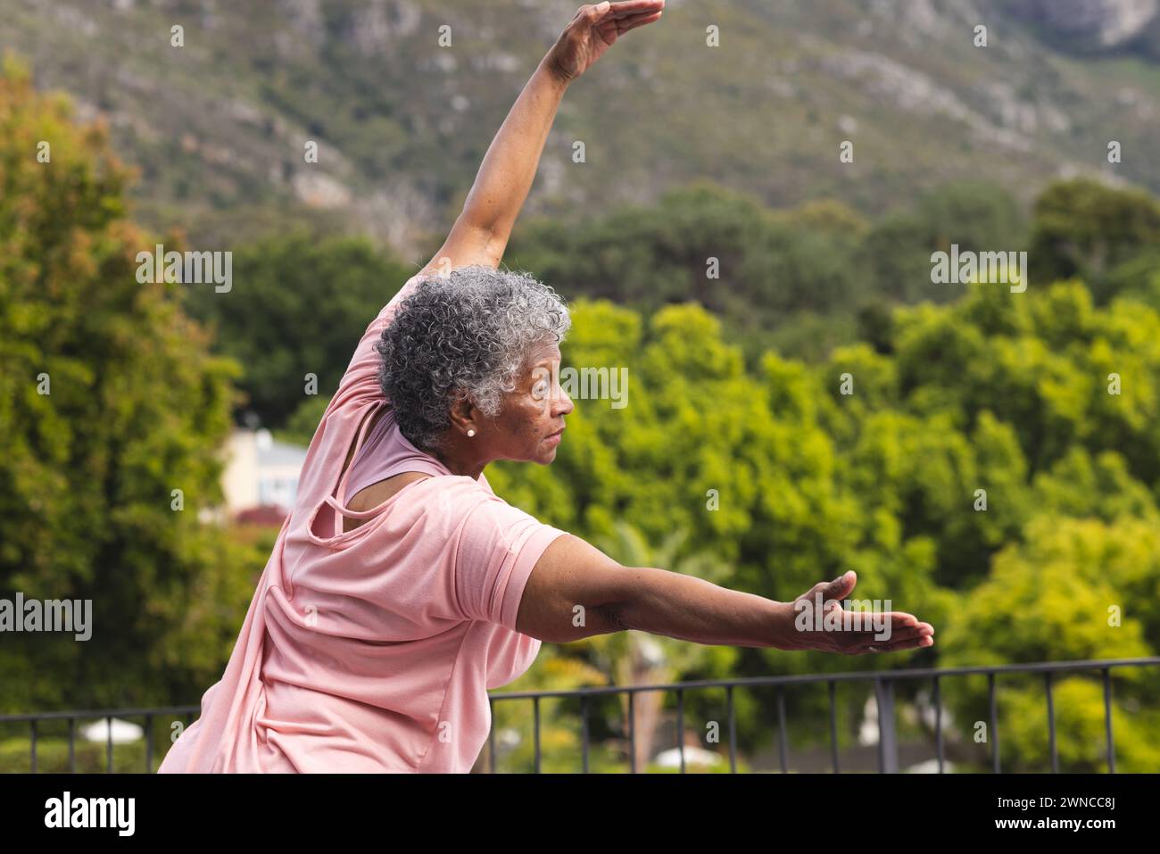 Femme biraciale senior avec les cheveux gris pratique le yoga à l'extérieur Banque D'Images