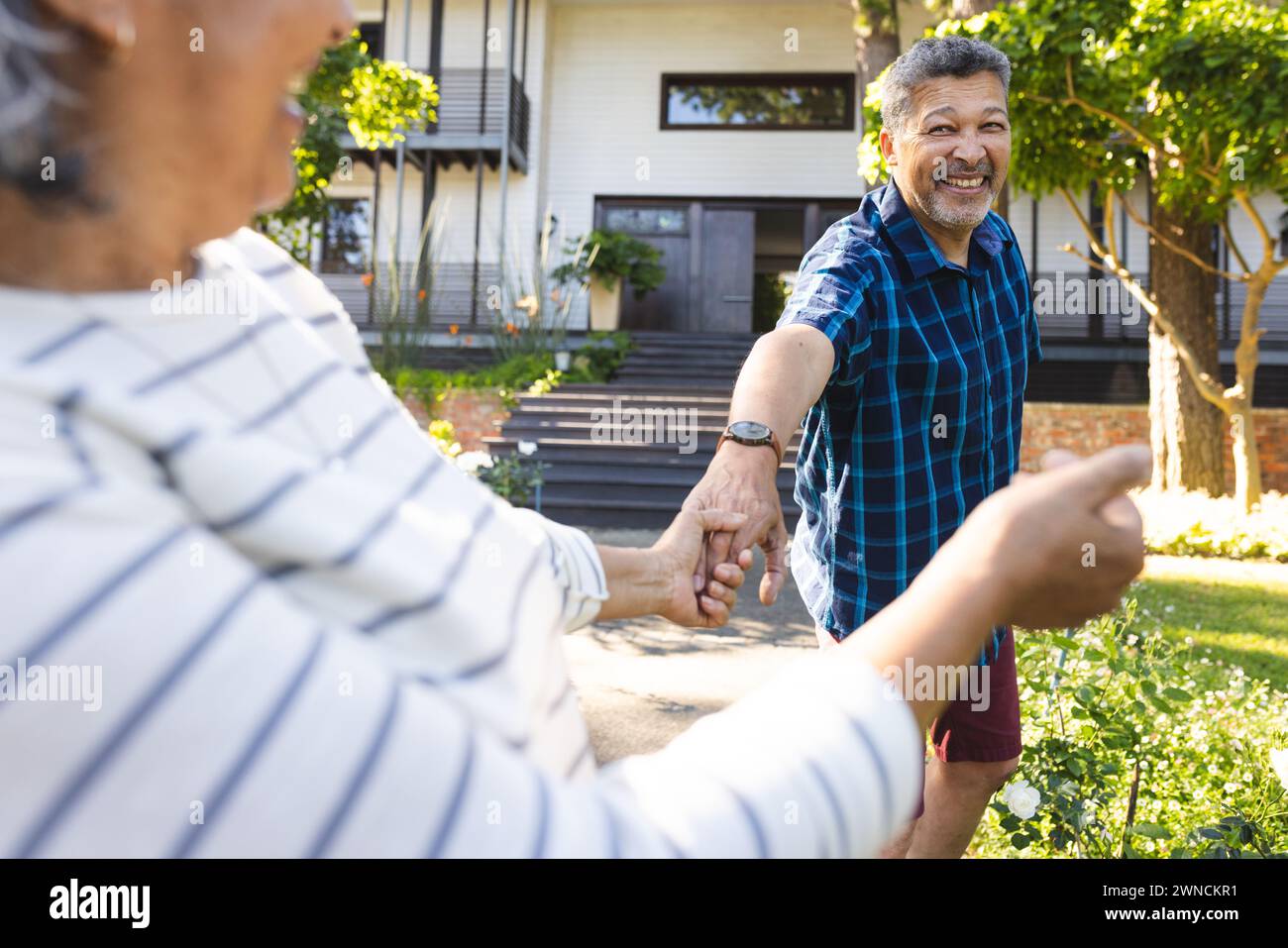 Femme biraciale senior mène un homme biracial souriant par la main à l'extérieur Banque D'Images