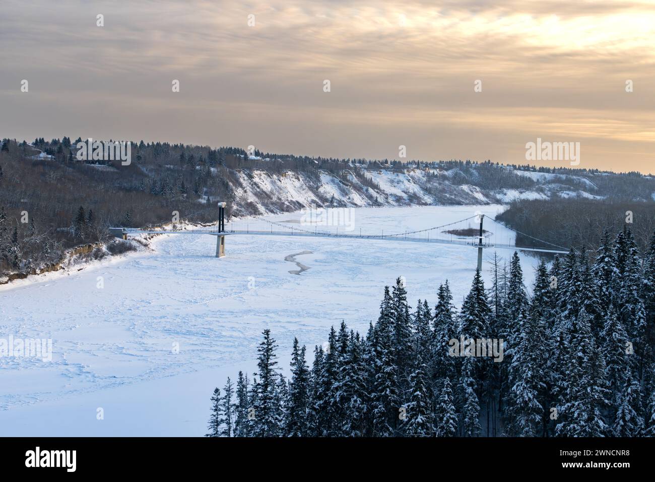 Vue sur le pont piétonnier de Fort Edmonton en saison hivernale avec un ciel de coucher de soleil rougeâtre sur le côté est Banque D'Images